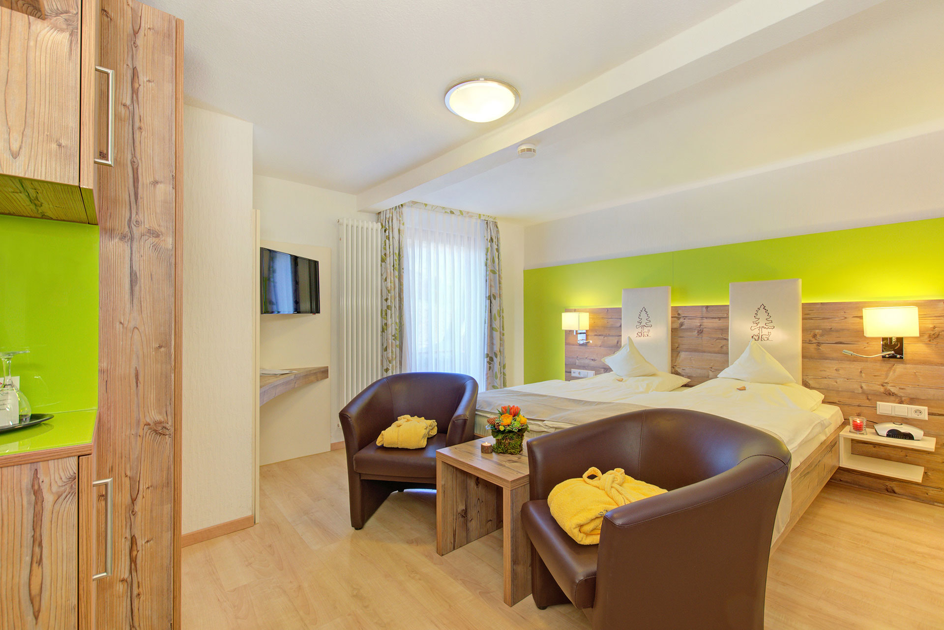 doppelzimmer mit braunen ledersesseln und gelben bademäntel in hotel
