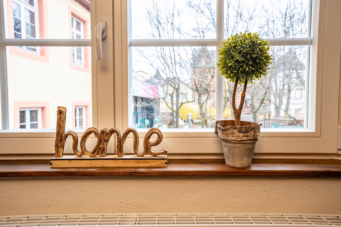 schild home und bäumchen auf fenstersims mit blick aus dem fenster - ferienwohnung fotografieren