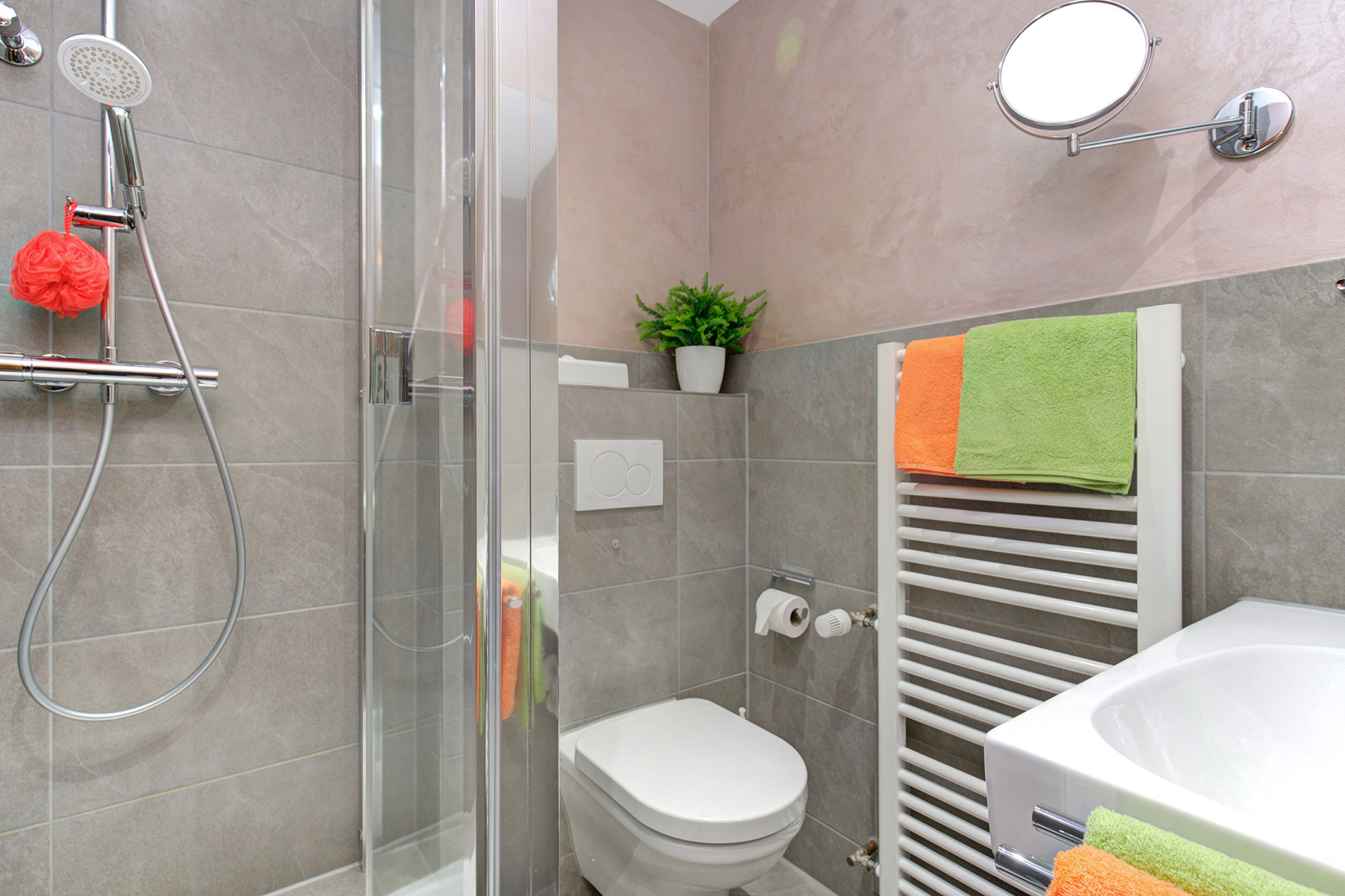 badezimmer mit grü orangenen handtüchern und grünpflanze in hotel