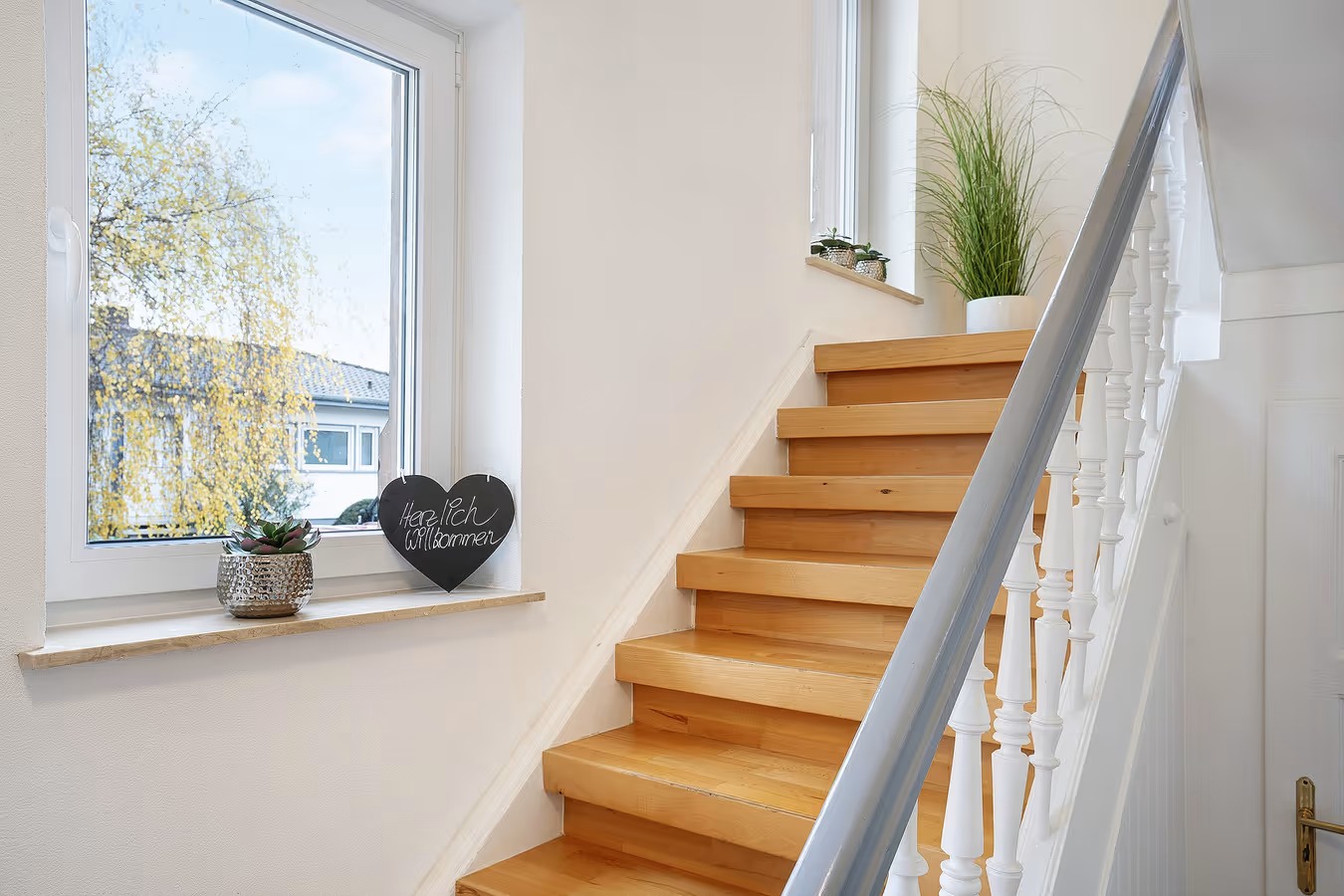 modernisierte holztreppe zum ersten obergeschoss mit willkommensherz am fenster