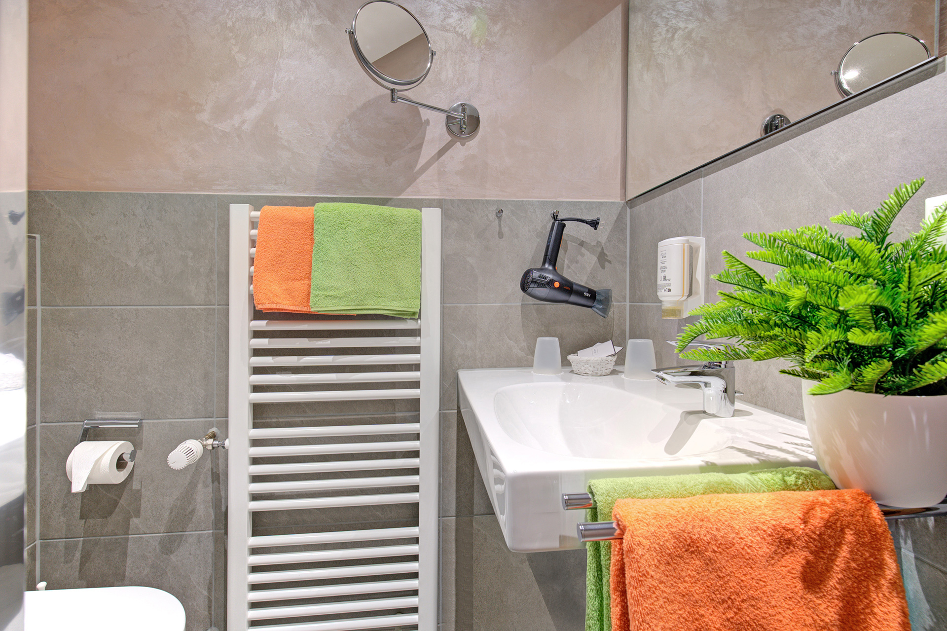 hotelfoto kleines badezimmer mit grünen und orangenen handtüchern sowie farn