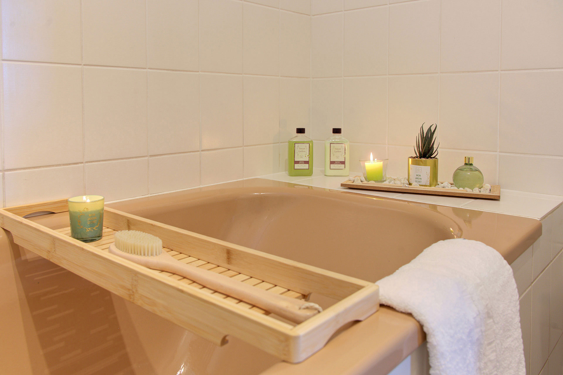 blick auf hellbraune badewanne mit holzbrett und accessoires