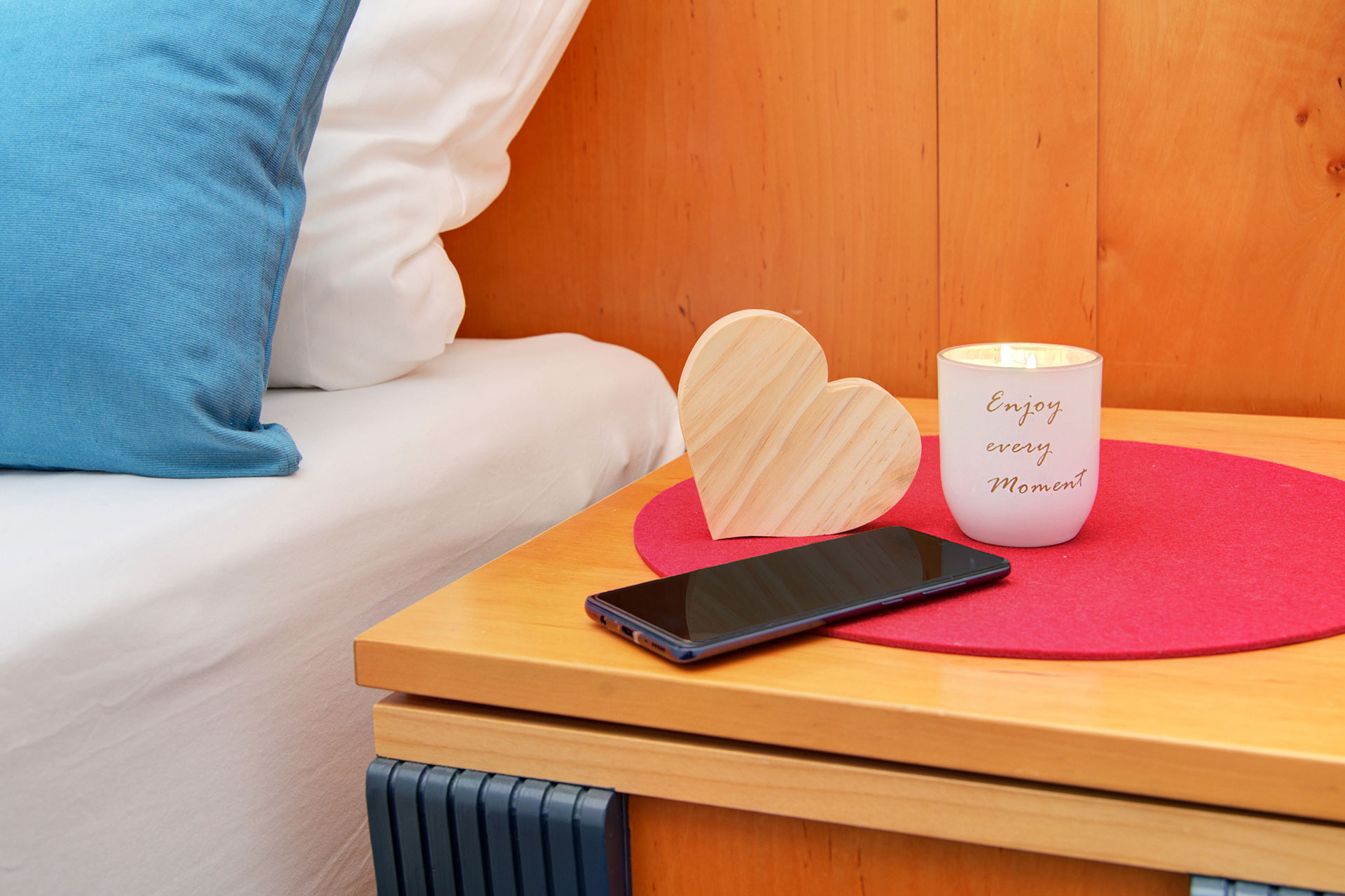 nachttisch mit smartphone holzherz und teelicht mit aufschrift enjoy every moment - ferienwohnung fotografieren