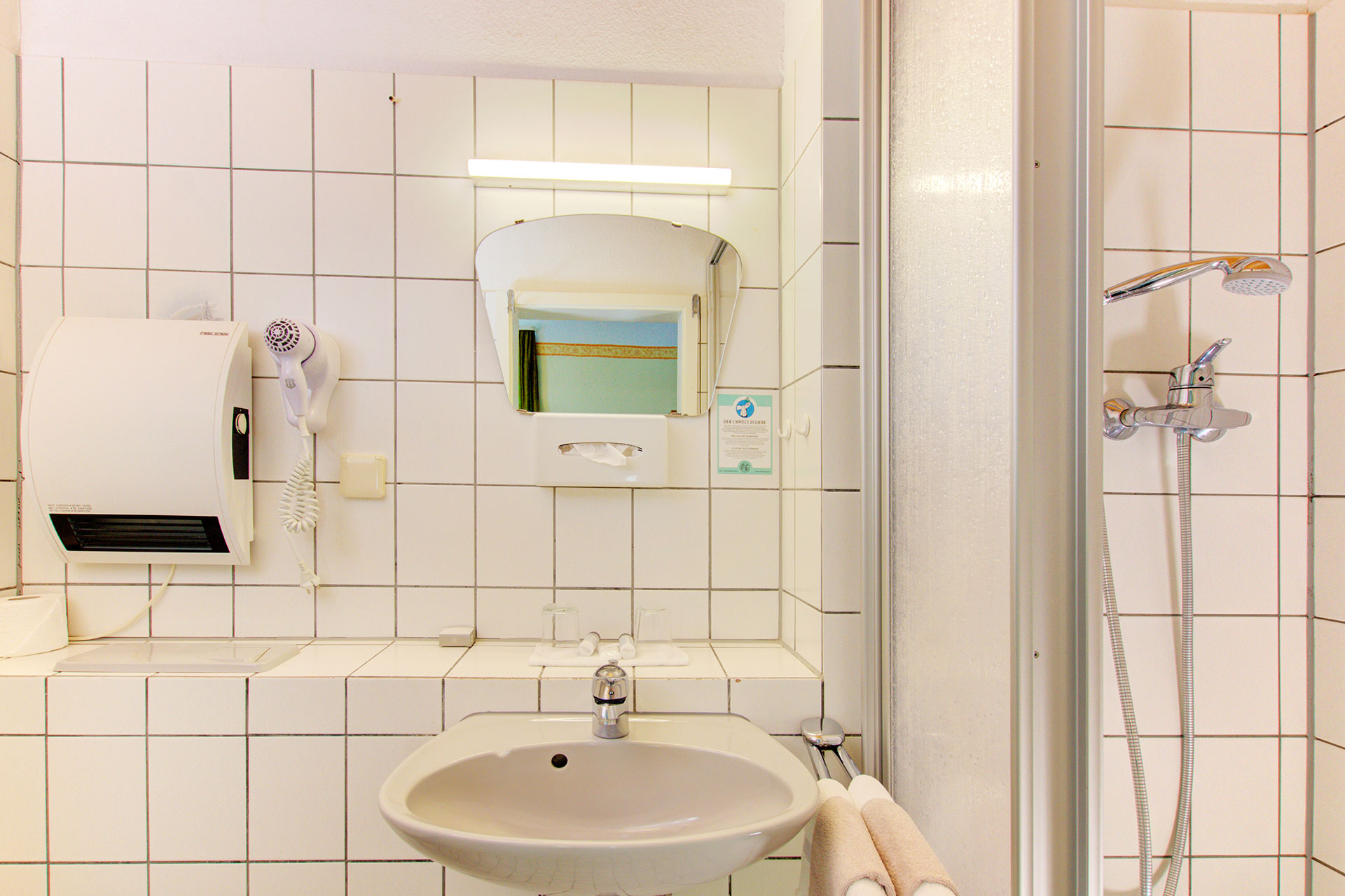 hotelfoto badezimmer in weis mit waschbecken und dusche