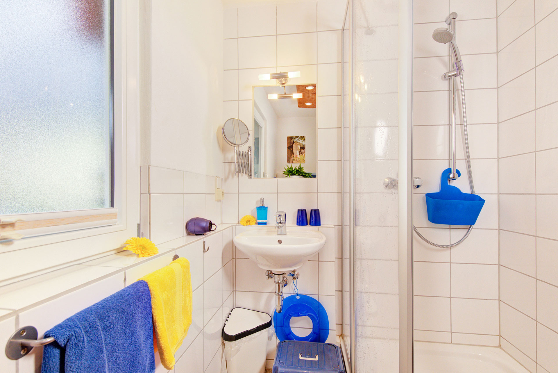 Badezimmer mit blauen und gelben handtüchern und aufstieghilfe in Ferienwohnung