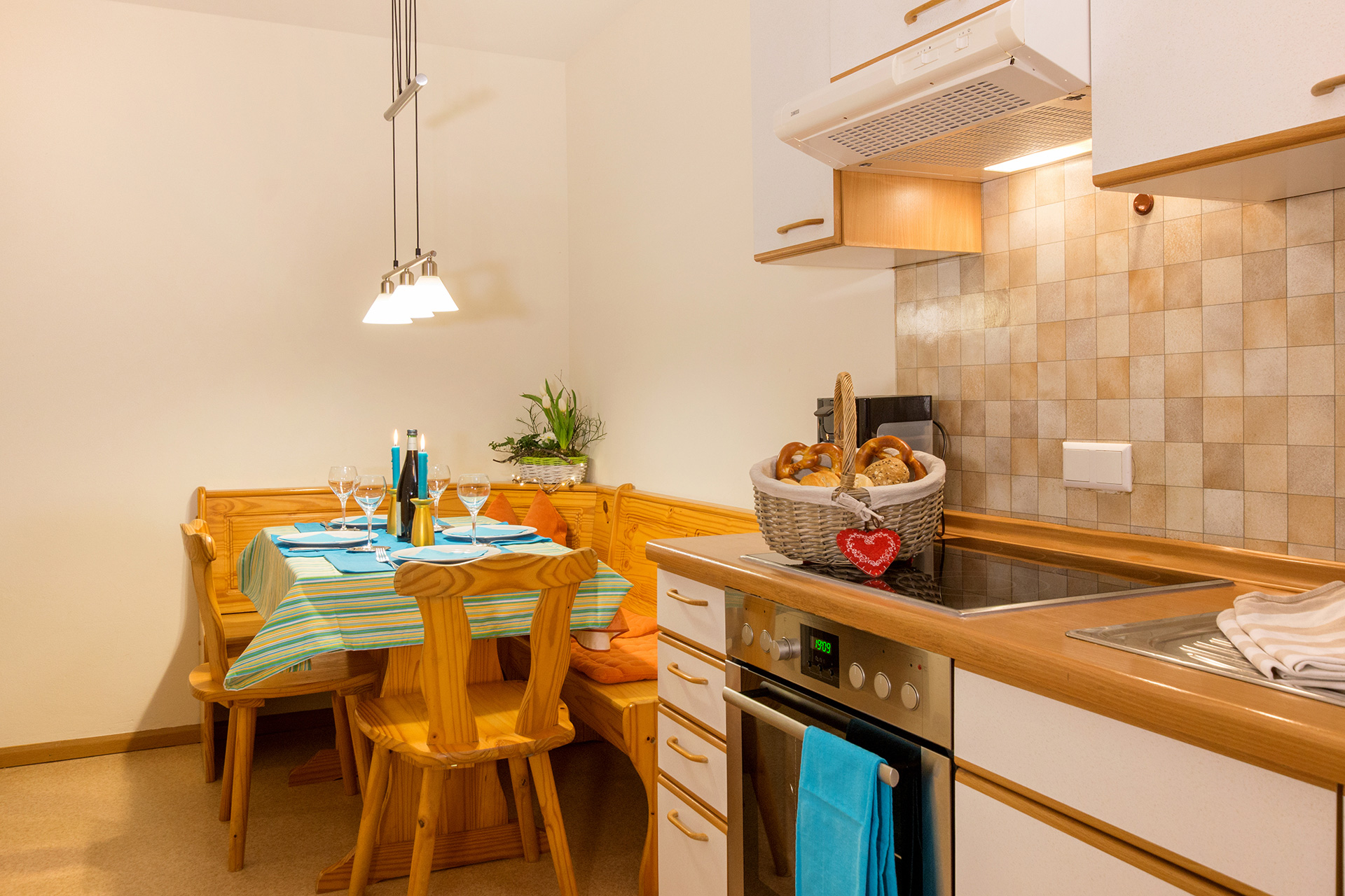 küche mit türkis eingedecktem essbereich und sitzbank in ferienwohnung
