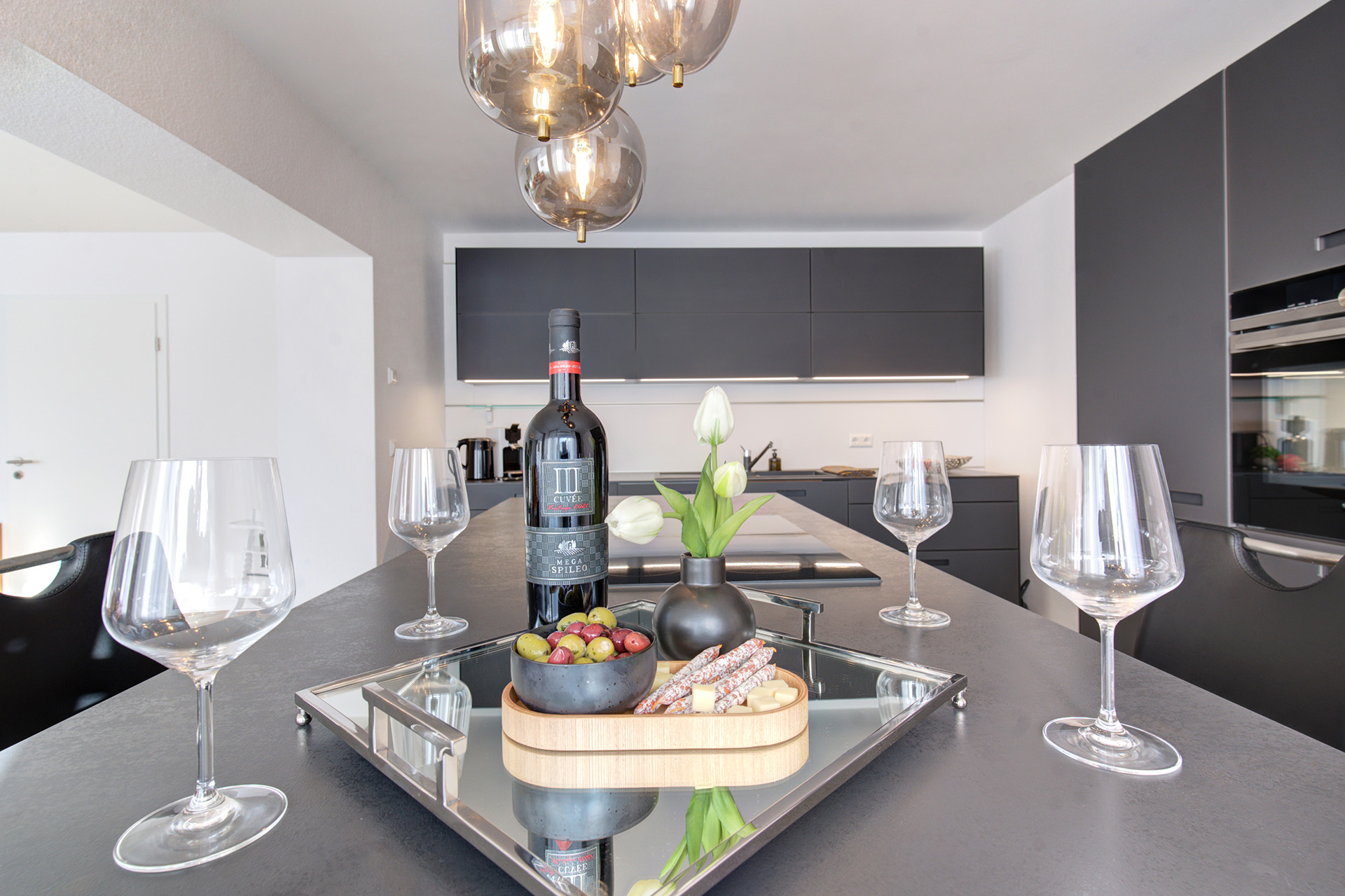 ferienwohnung fotografieren - gedeckter küchenbartisch mit gläsern, wein und Appetizern in der ferienwohnung