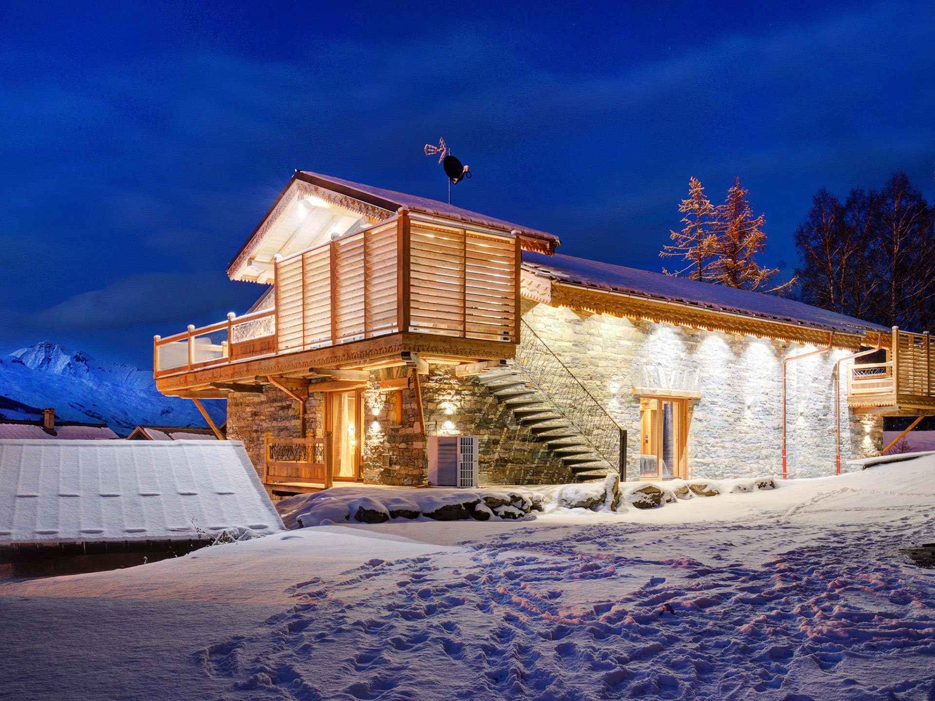 Beleuchtetes steinernes Ferienhaus in Abendstimmung mit Bergkulisse