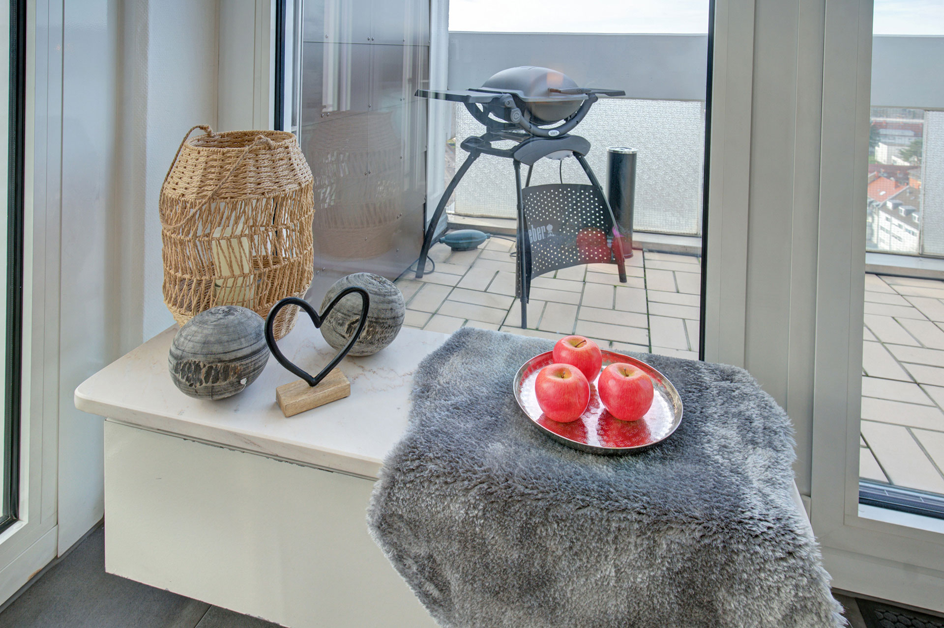 blick durchs fenster auf den balkon mit BBQ