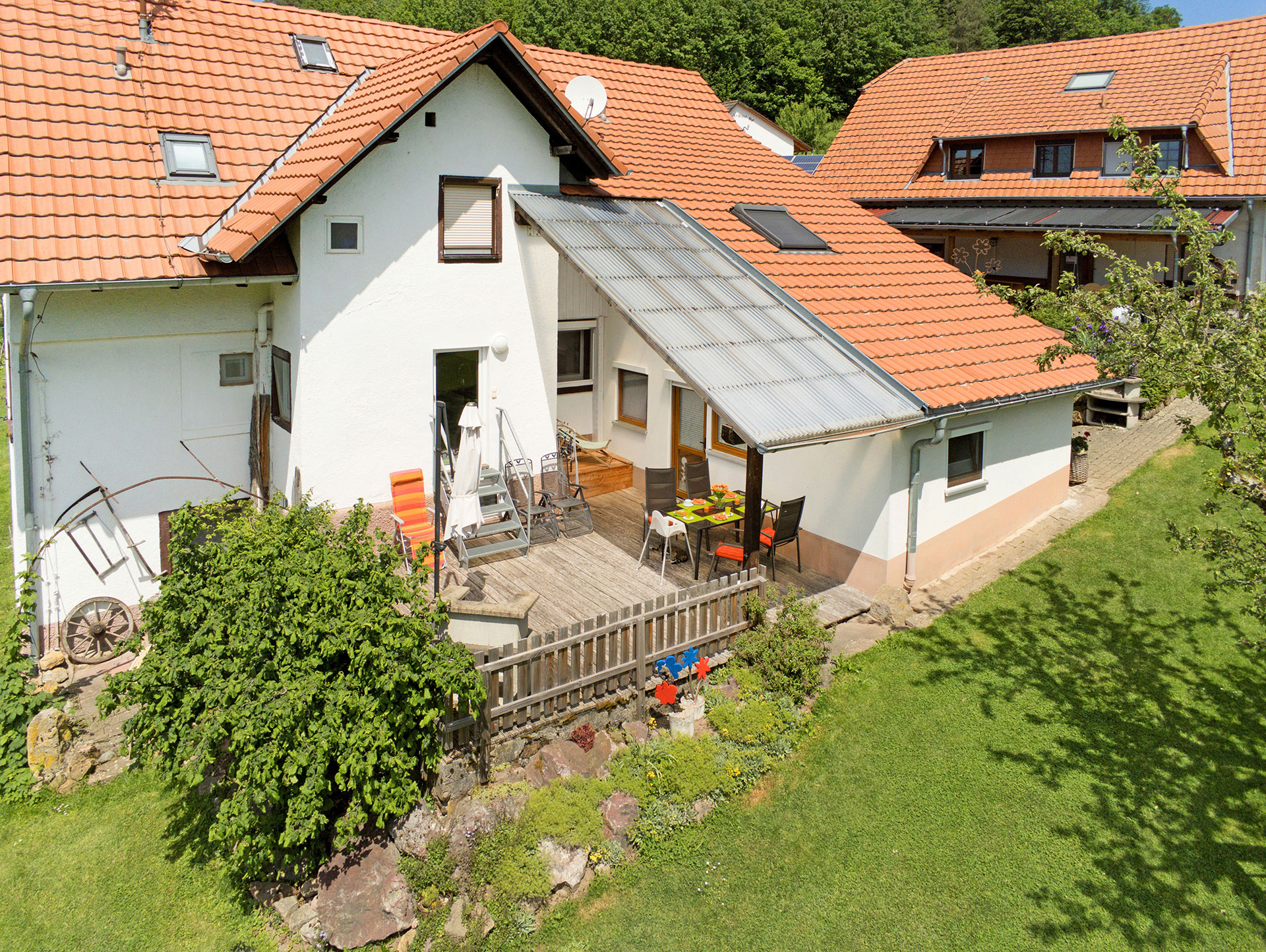 luftaufnahme ferienhaus seitlich mit terrasse schirm und gedecktem tisch