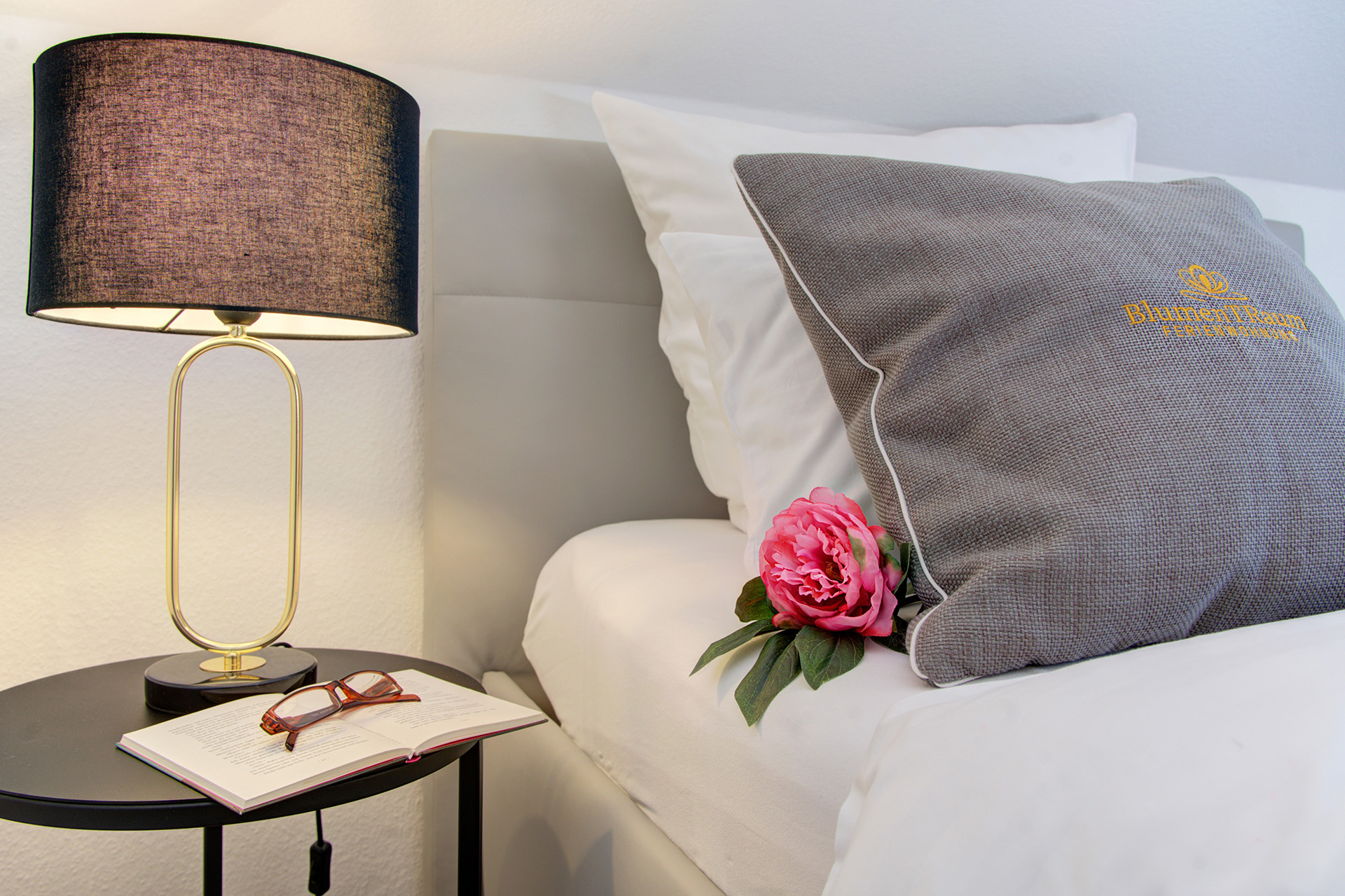 ferienwohnung fotografieren - Schlafzimmer mit dekorativen Kissen mit pfingstrose und Nachttisch mit lampe