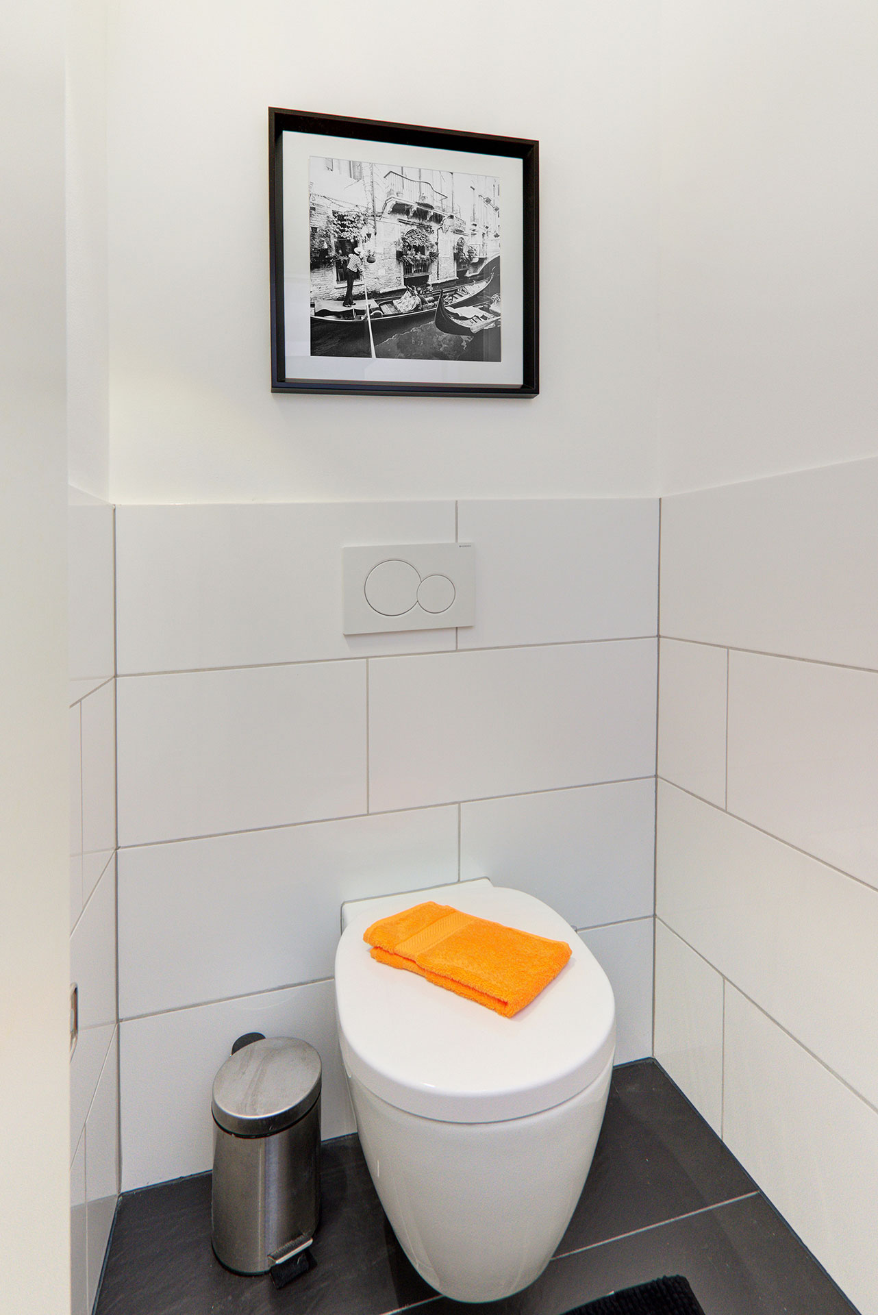 apartment fotografieren hochwertiges WC mit bild und organenem handtuch