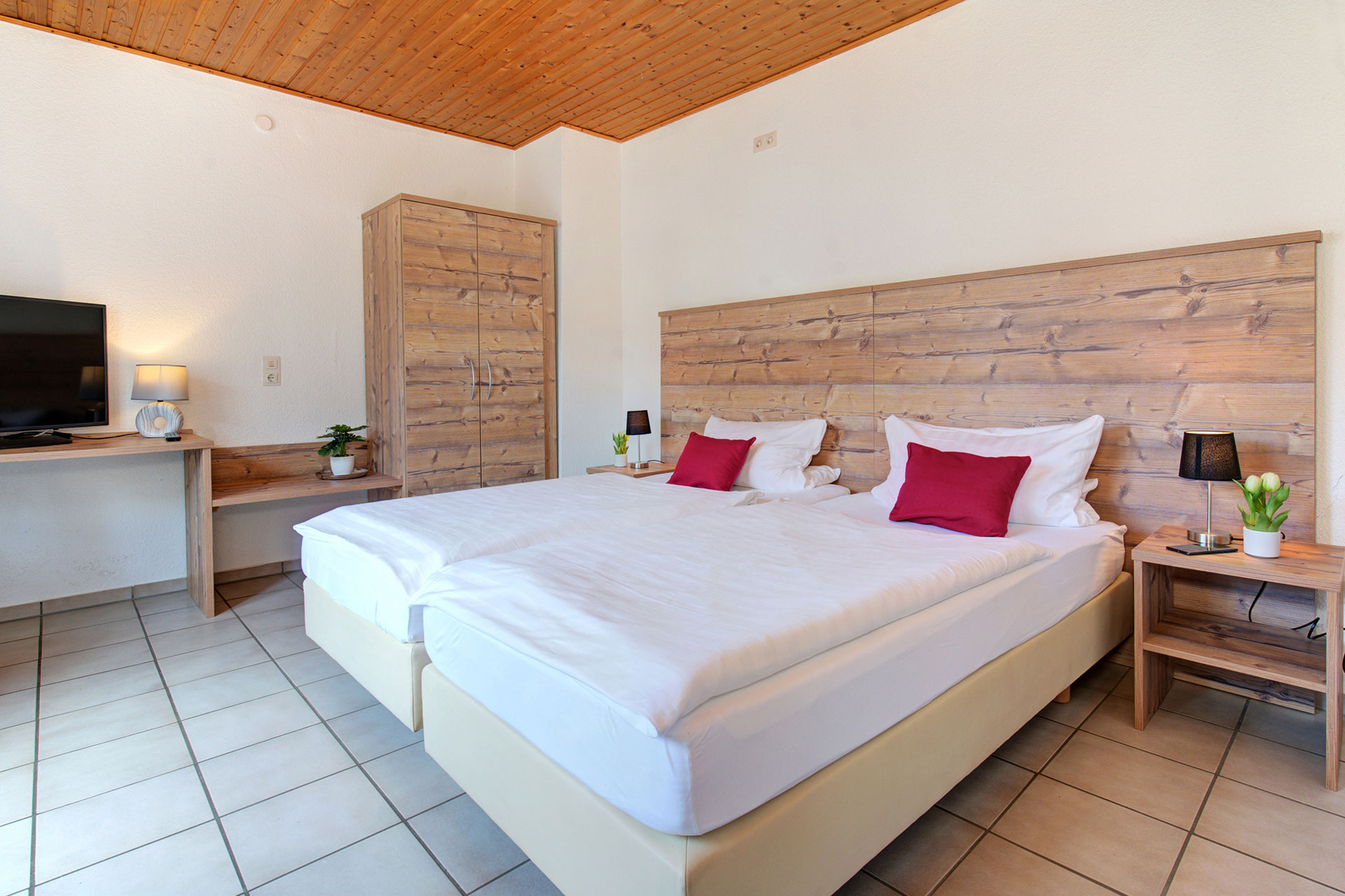 doppelbett mit roten kissen und blick auf schrank in ferienhaus