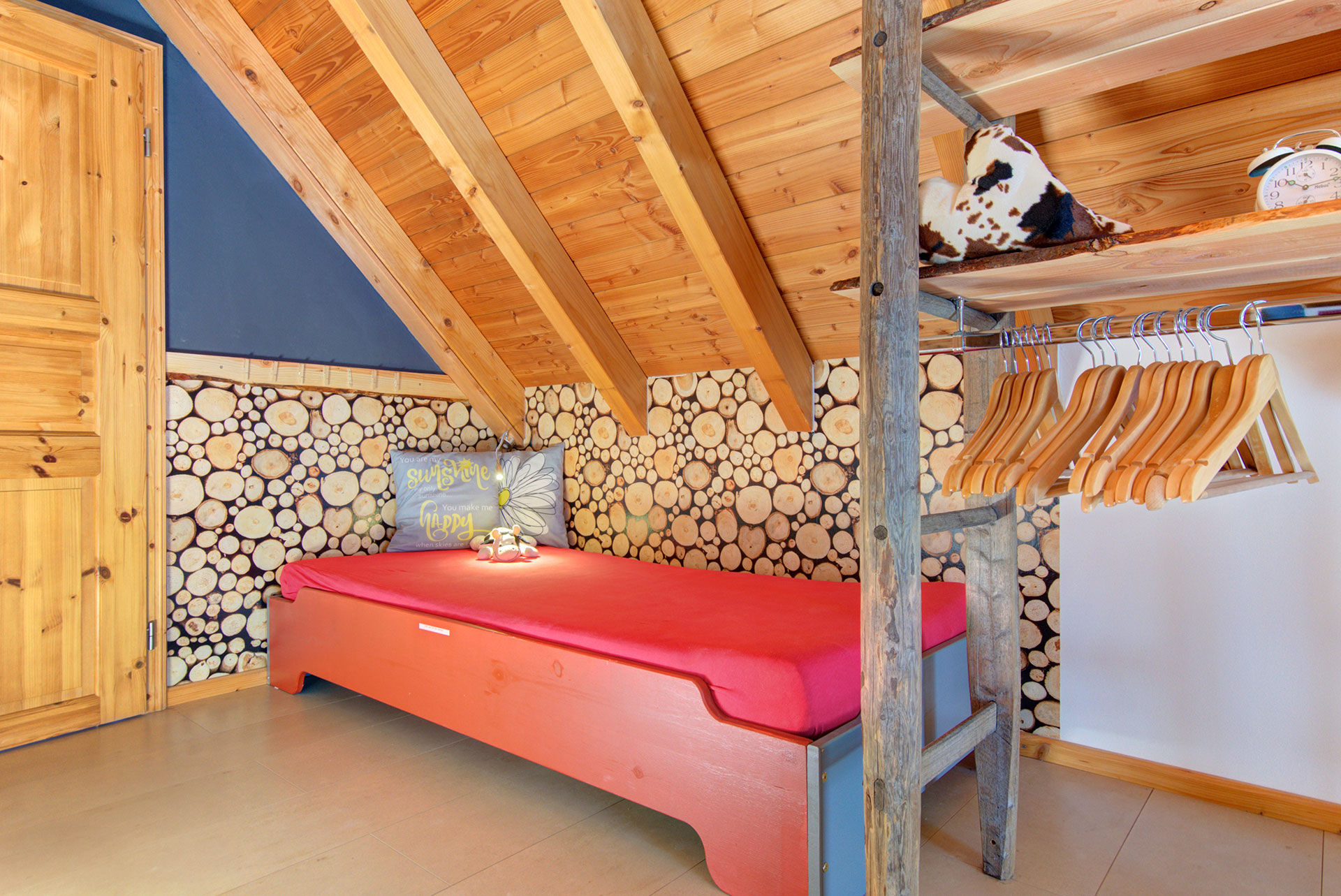 rotes bett mit kissen und garderobe unter dachschräge im Ferienhaus