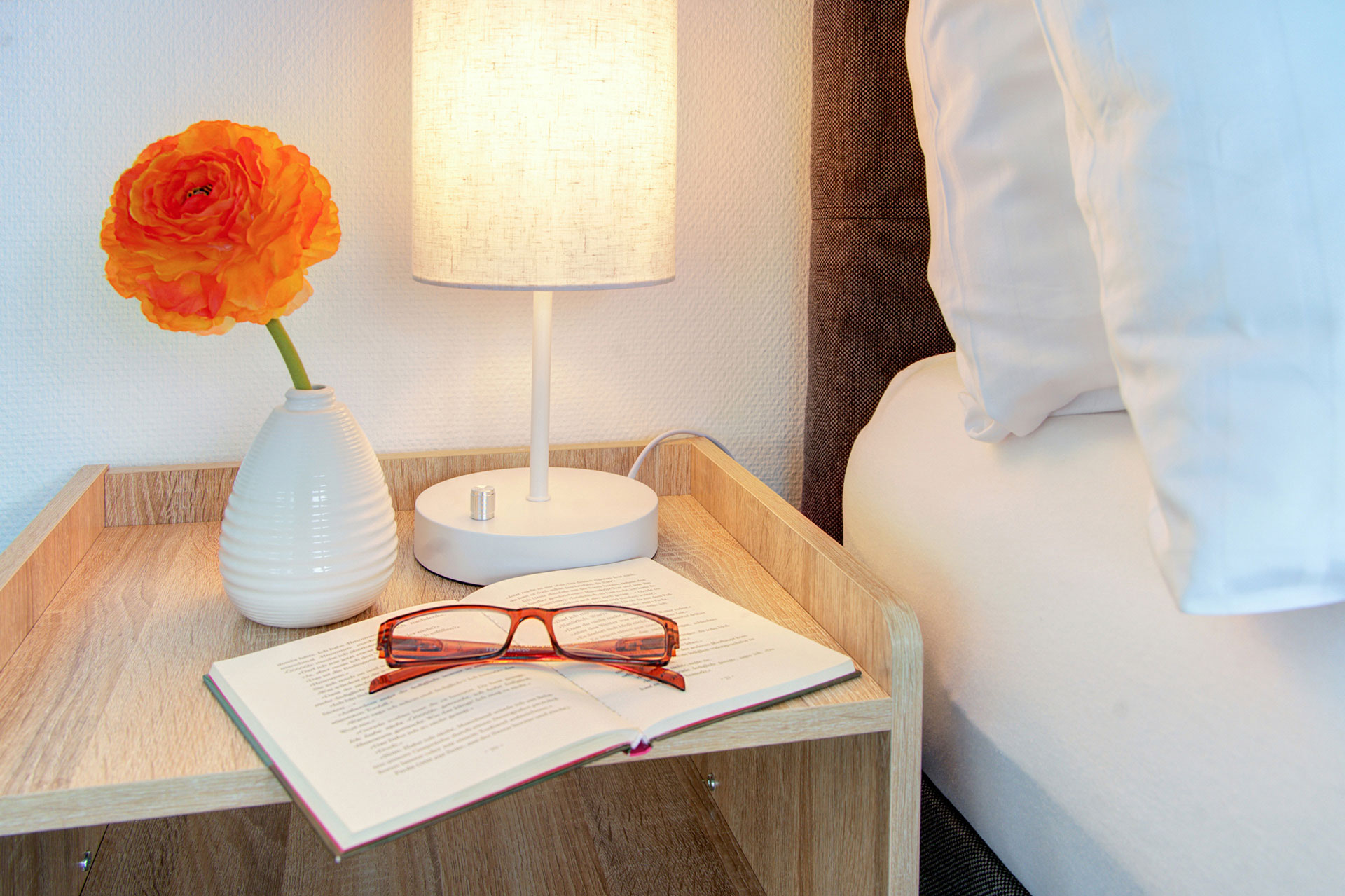 nachttisch mit blume brille und buch in penthouse
