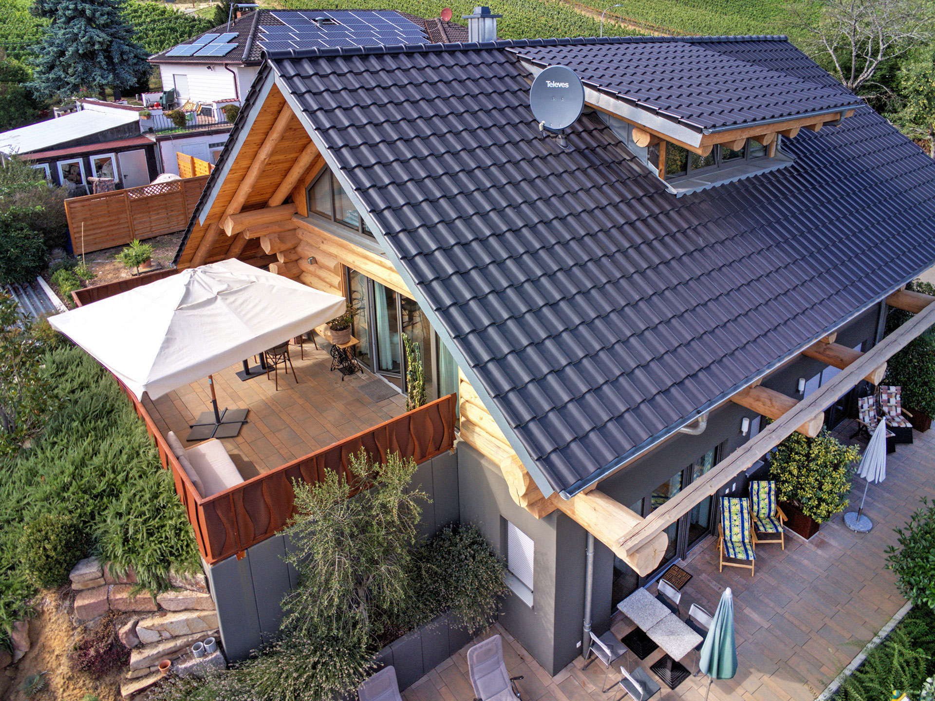 Architektonisches Holzhaus nahe der Deutschen Weinstraße, aufgenommen aus der Vogelperspektive mit Blick auf Terrasse und Schirm