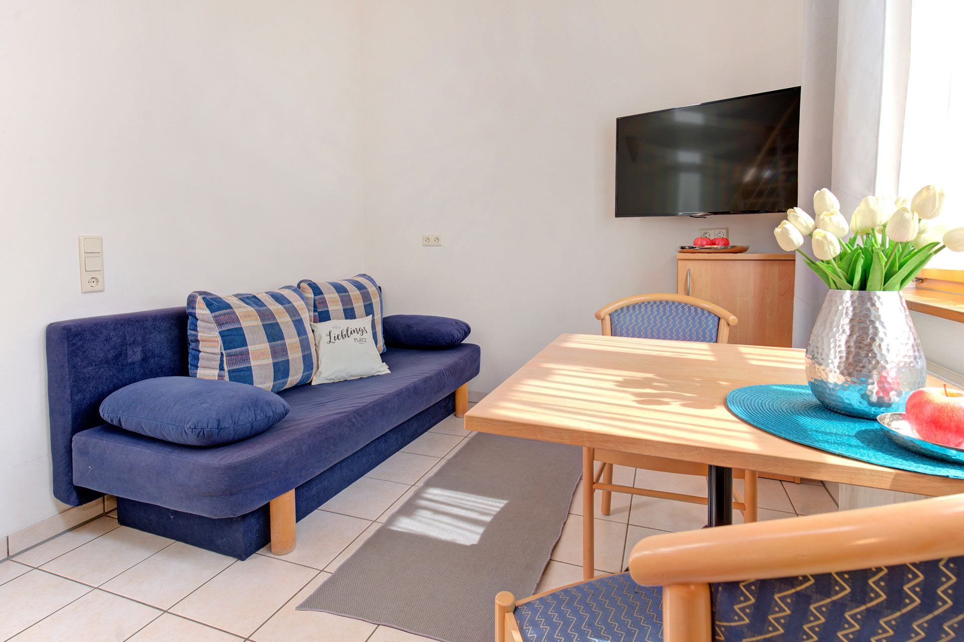 Wohnraum der Ferienwohnung für zwei Personen mit blauem Sofa und TV - airbnb fotograf