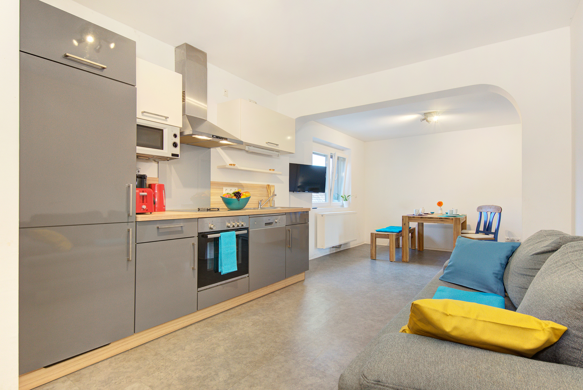 monteurzimmer fotografieren graues sofa mit okker decke und grosser küchenzeile