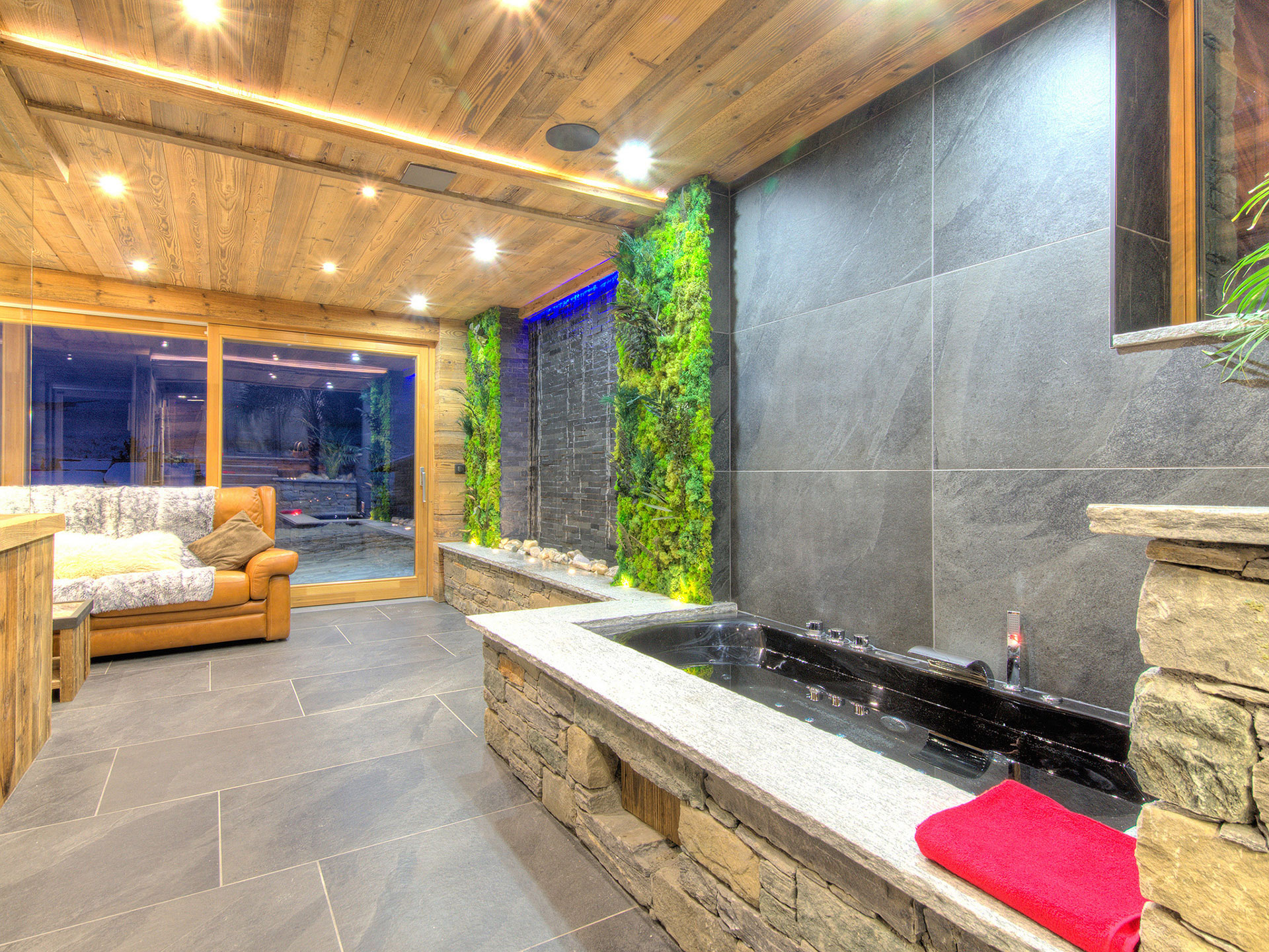 Geräumiger Spa Bereich mit hydrospeed becken und gemütlichem Sofa mit blick zur Terrasse
