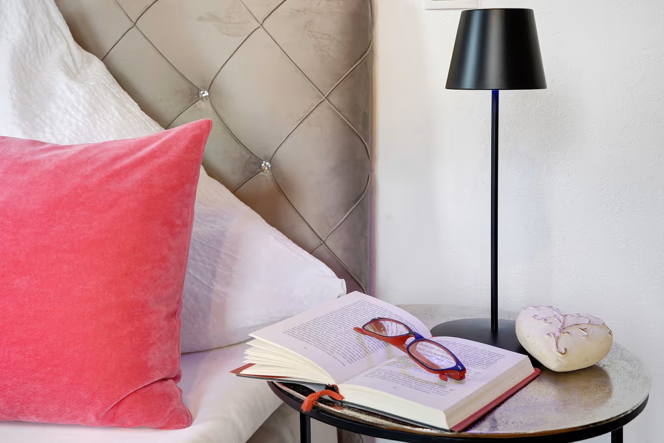 ferienwohnung fotografieren - Arrangierte Nahaufnahme vom nachttisch mit buch brille und leuchte