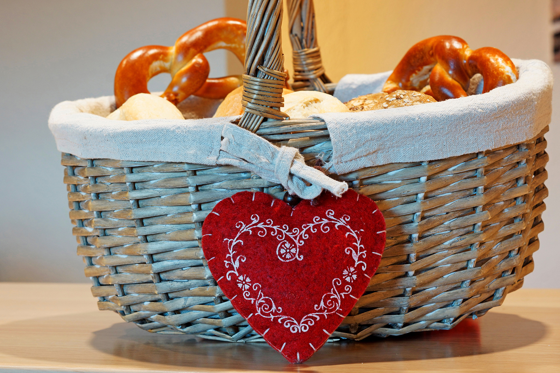 korb mit brezeln und hängendem roten herz in ferienwohnung