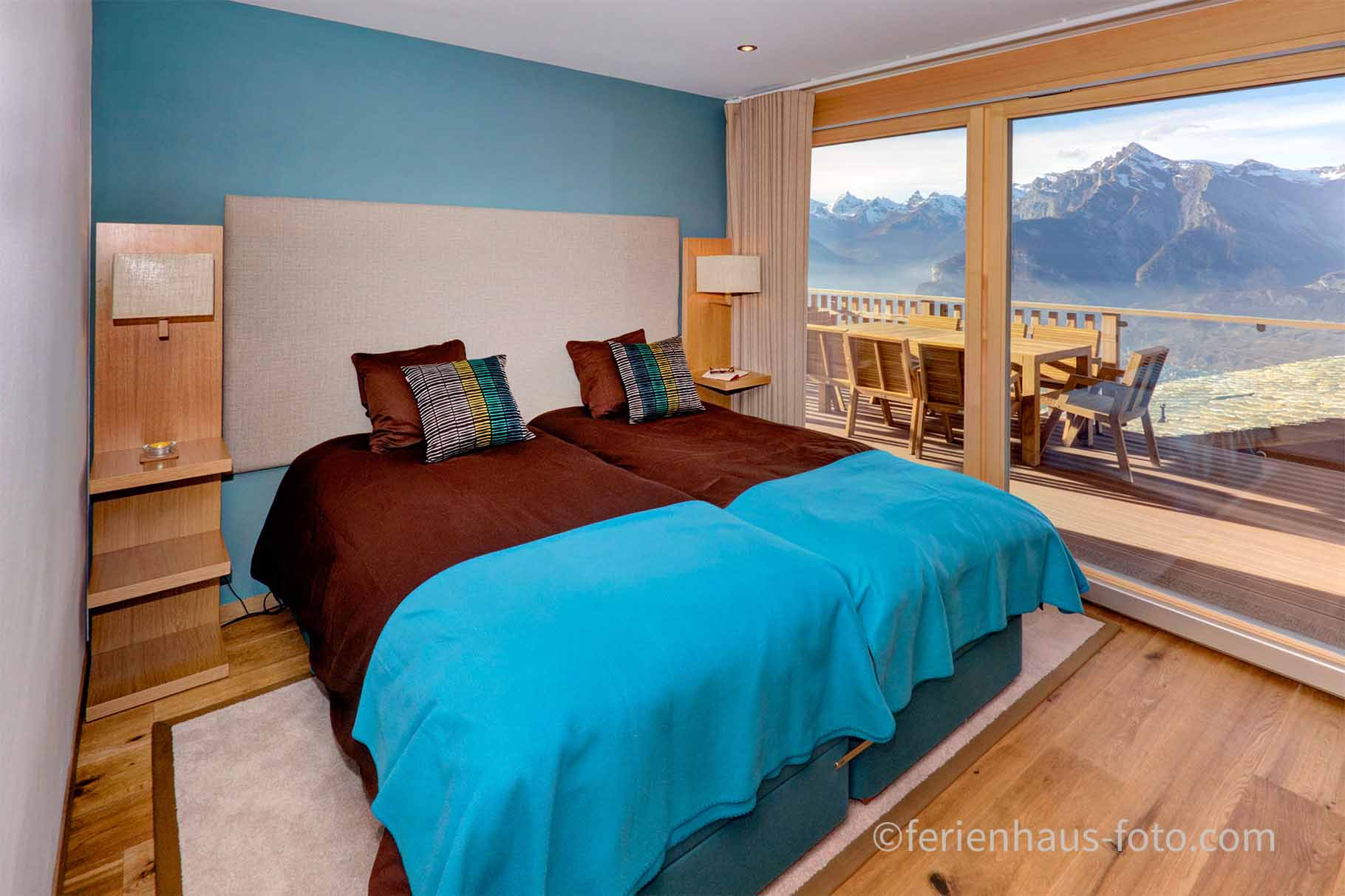 ferienhaus foto schlafzimmer in braun türkis und panoramafenster mit berge