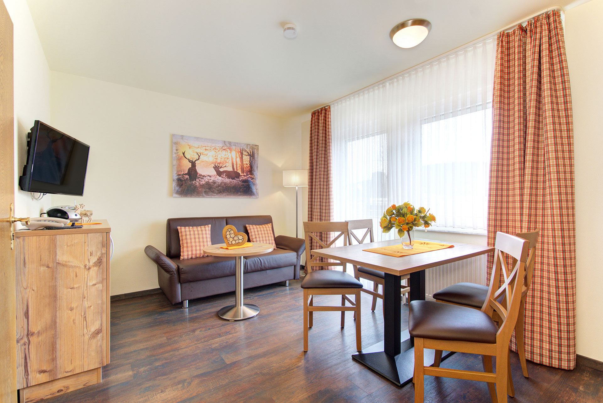 foto ferienwohnung essbereich mit blick auf esstisch mit vier stuehlen und organgefarbenem blumenstrauss