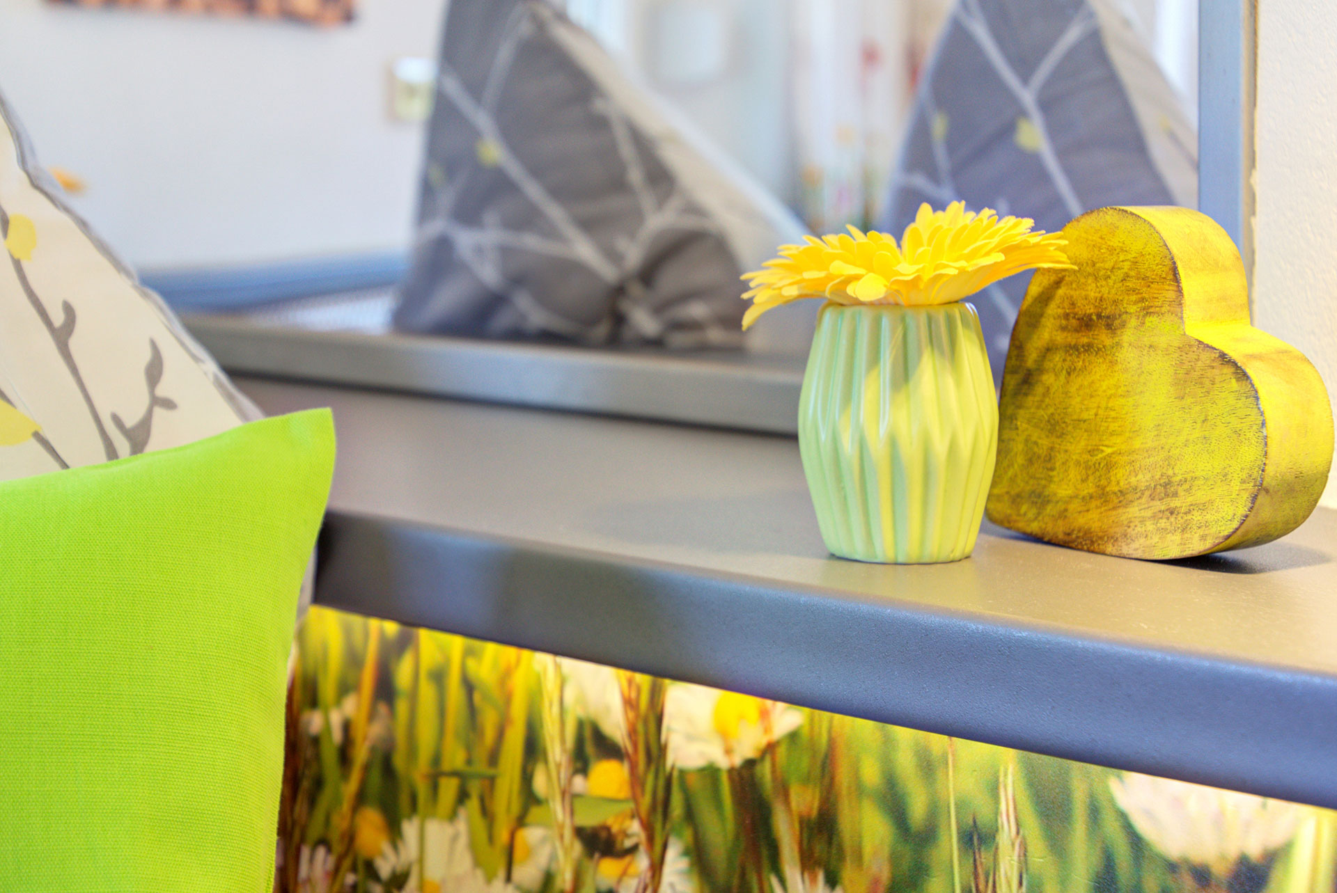 nachttischablage mit grüner kleiner vase und gelber gerbara in ferienwohnung