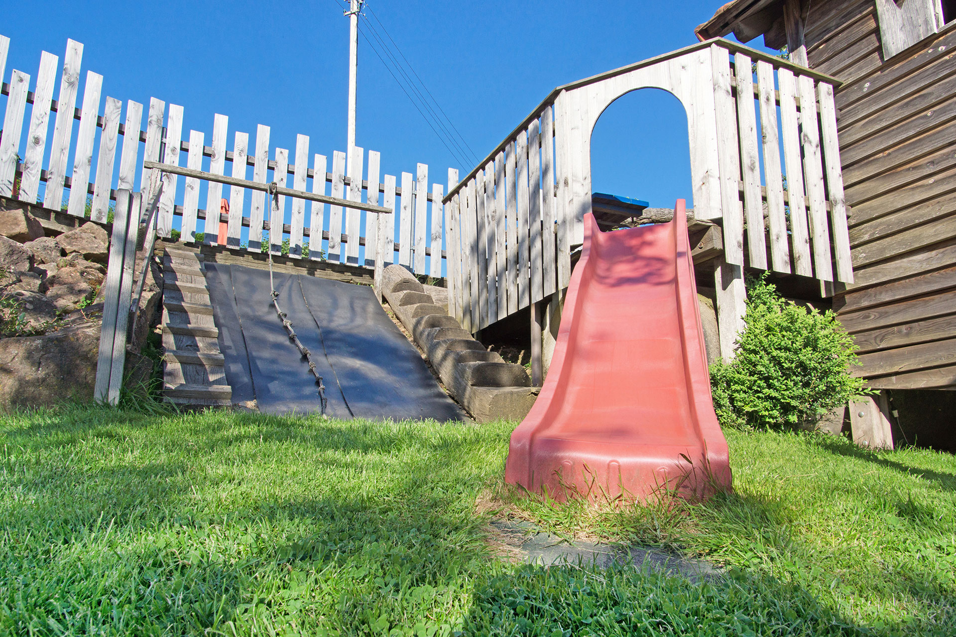 rote rutschbahn von unten mit gartenzaun im ferienhof