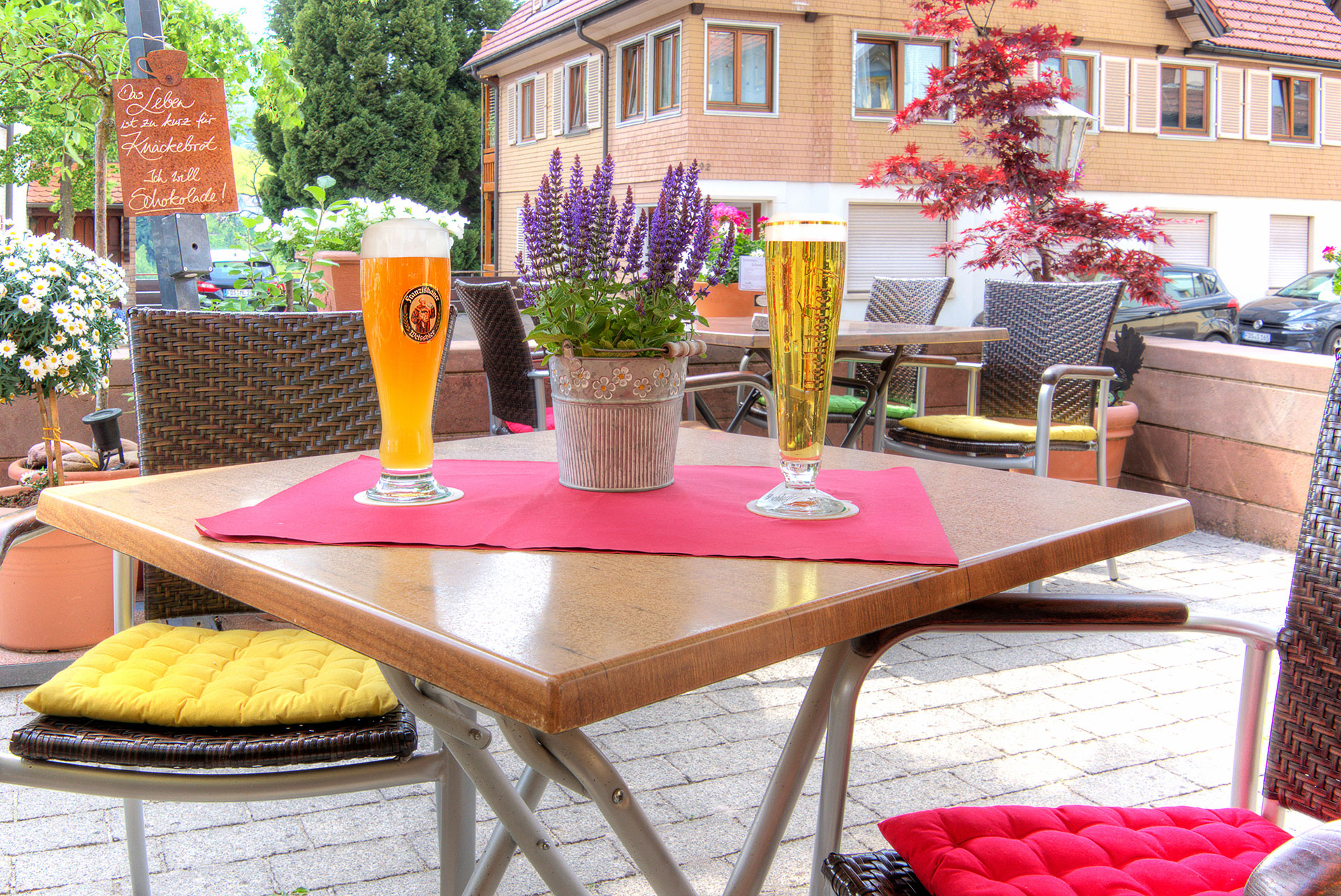 hotelfoto biergarten mit detailblick auf tisch mit zwei frisch gezapten bieren sowie hintergrund nachbarhaus