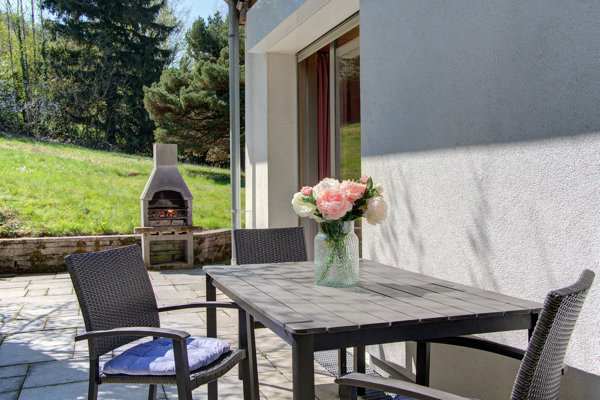 Terrasse mit Pfingstrosenstrauss und brennendem Grillkamin