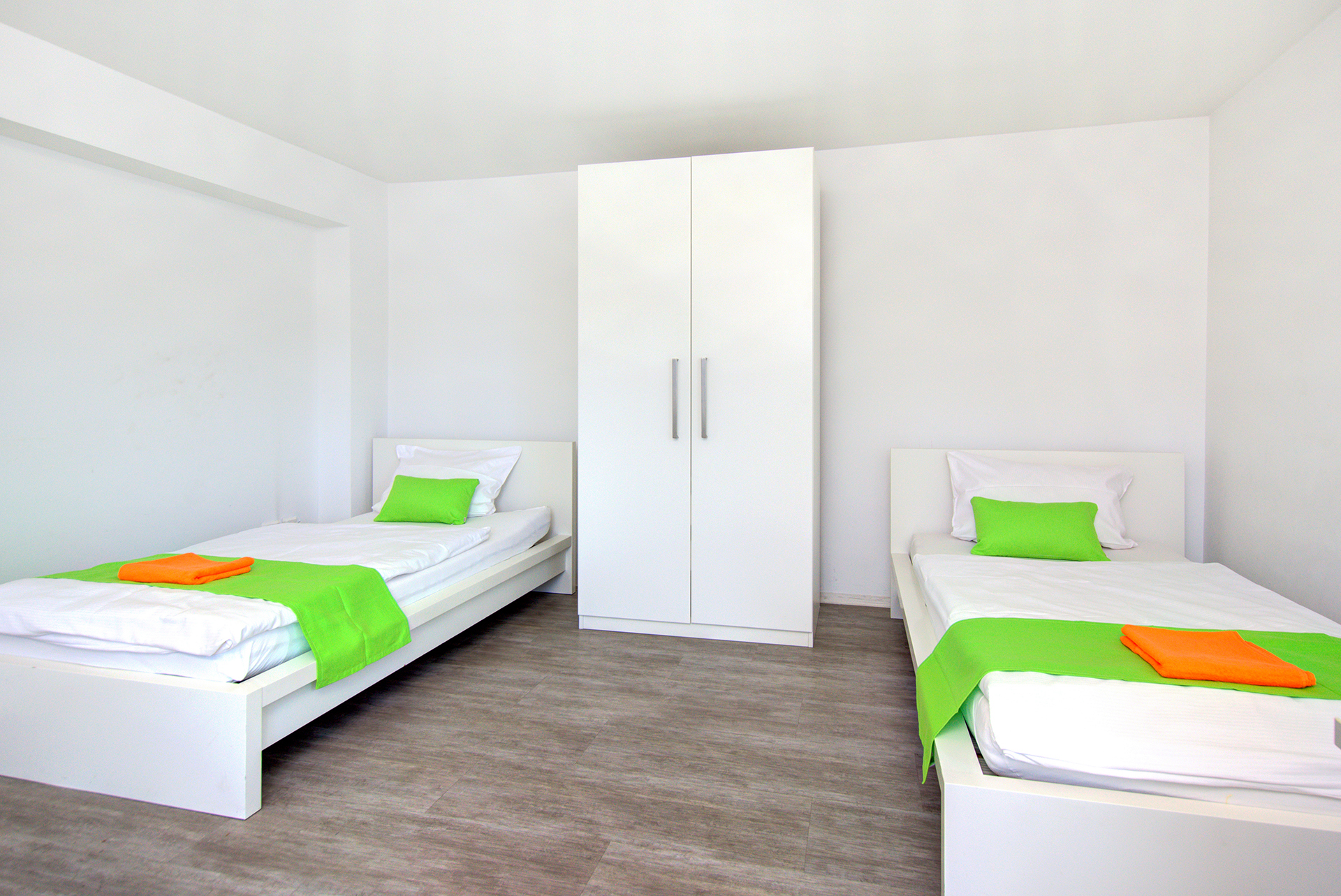 monteurzimmer fotografieren zimmer mit zwei einzelbetten und schrank mit grünen bettläufern und kissen