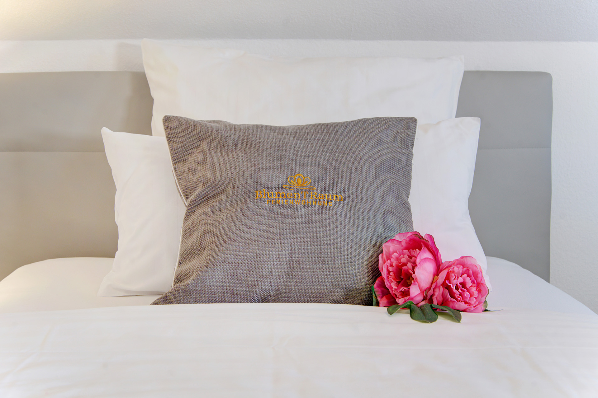 ferienwohnung fotografieren - hochwertiges kissen auf bett mit logo ferienwohnung