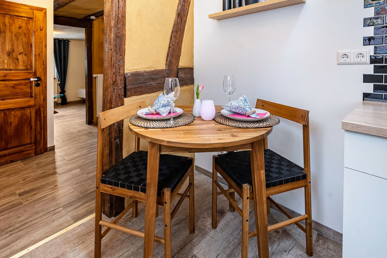 Essbereich mit Holztisch und -stühlen und mit zwei geschmackvollen Gedecken