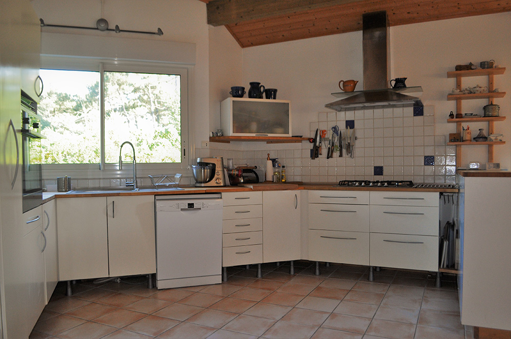 Dunkle Küche in einem Ferienhaus, hinter den Fenstern ist nur weißes Licht sichtbar
