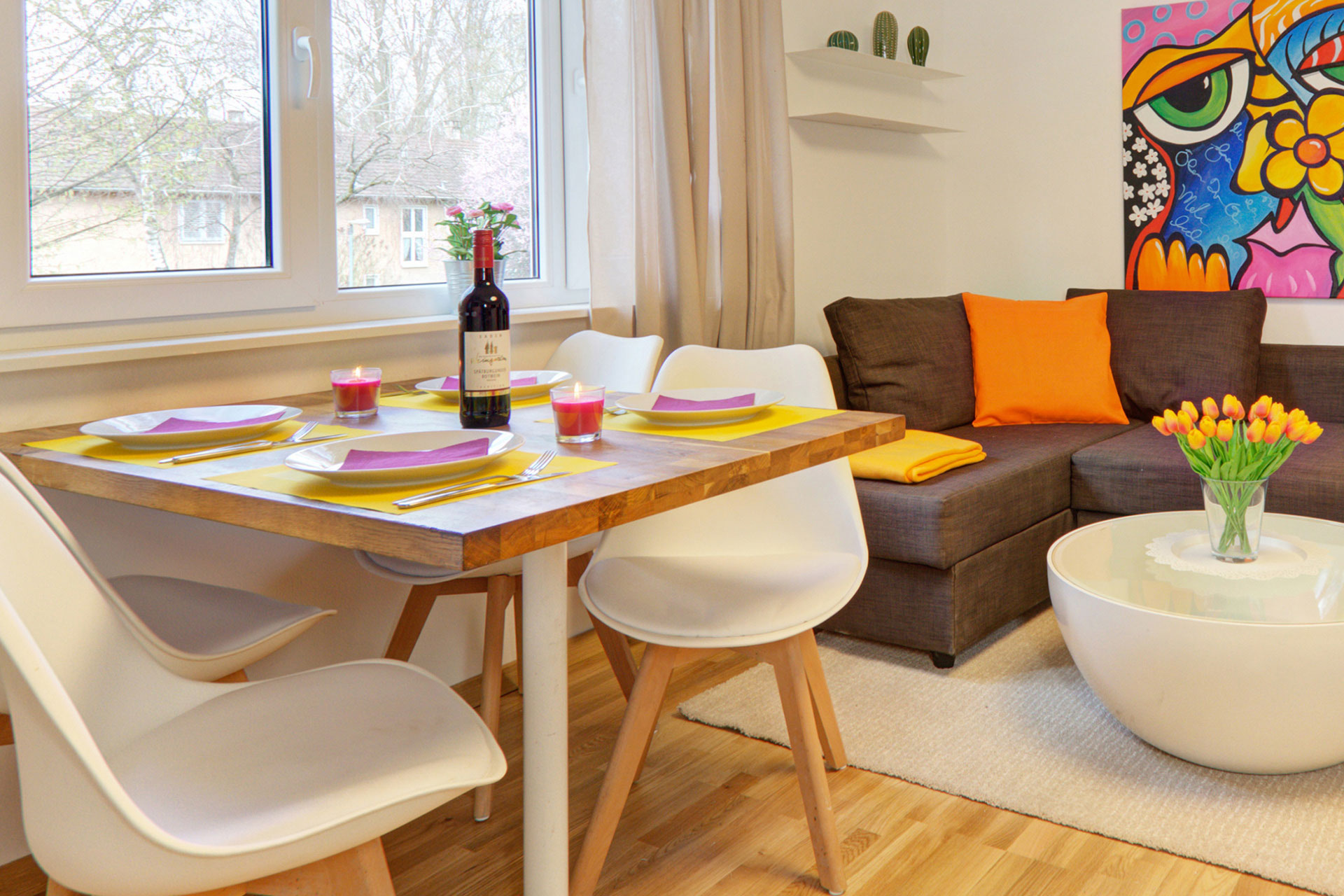 fotografin dekoriert esstisch in gelblila eingedeckt teelichter und orangener tulpenstrauss auf sofatisch