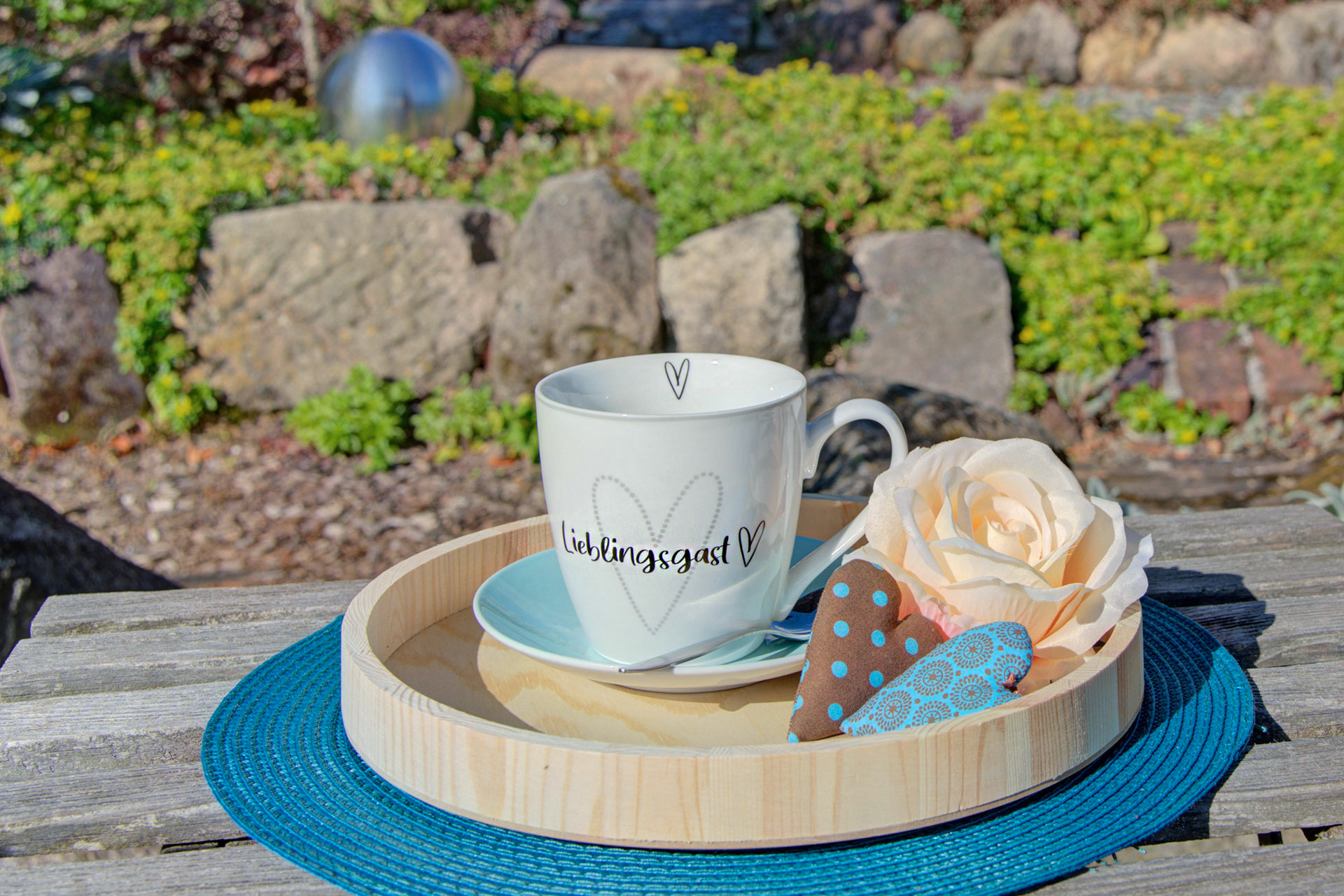 holztablett mit tasse lieblingsgast sowie rose und kleine herzen im Ferienhof