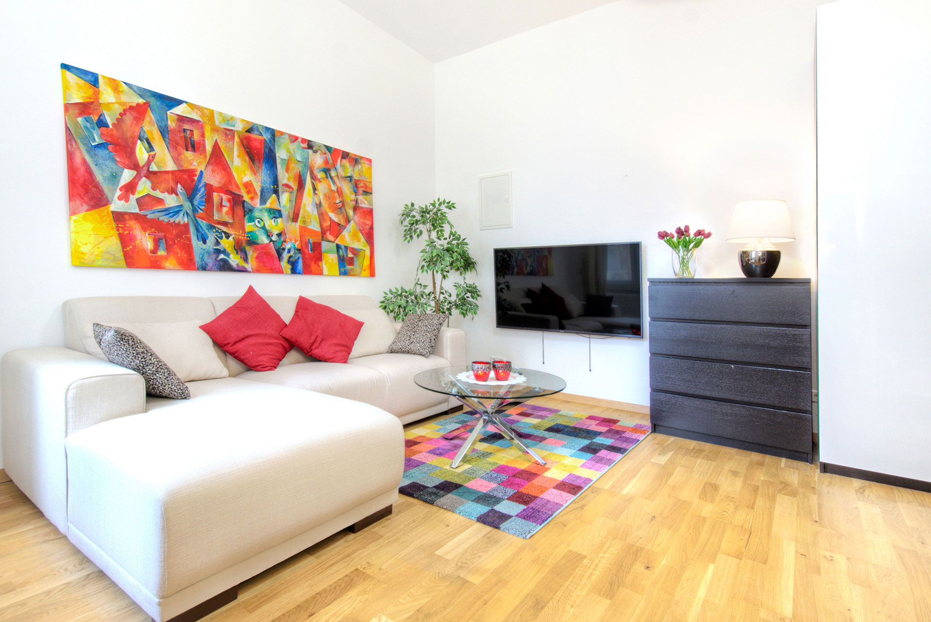 foto-apartment-wohnraum-sofa-rote-kissen-buntes-bild