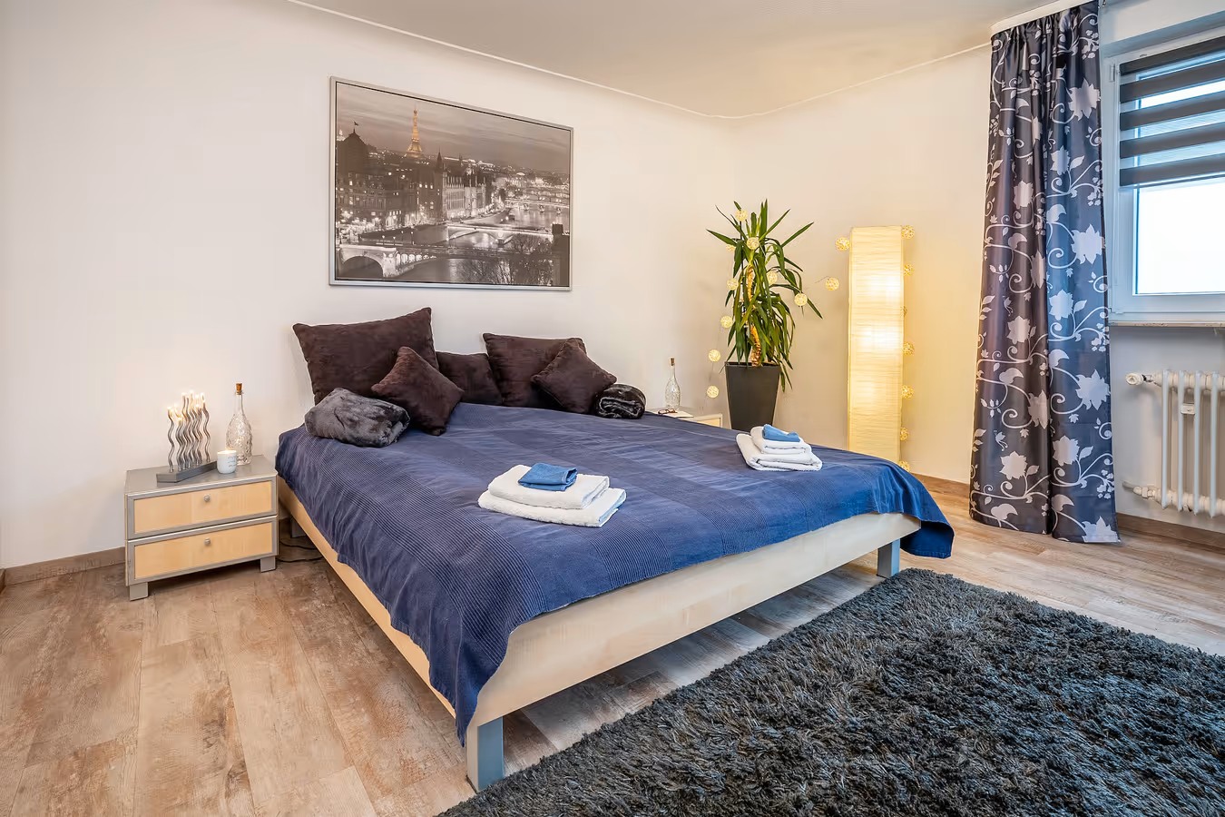 ferienwohnung schlafzimmer mit blauen Bettsachen und papierstehleuchte