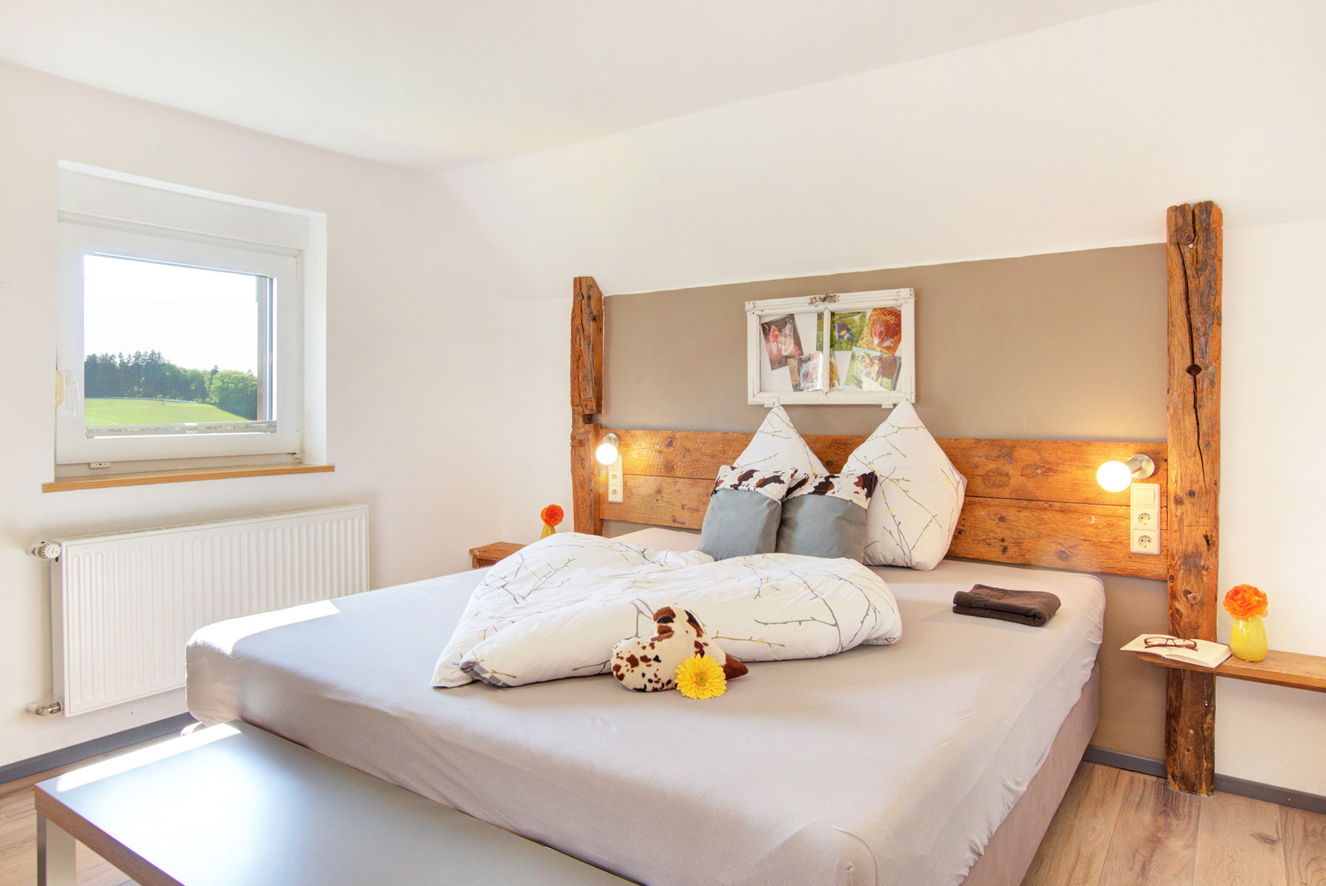doppelbett aus holz mit gerbara vor bettwäsche in Ferienwohnung