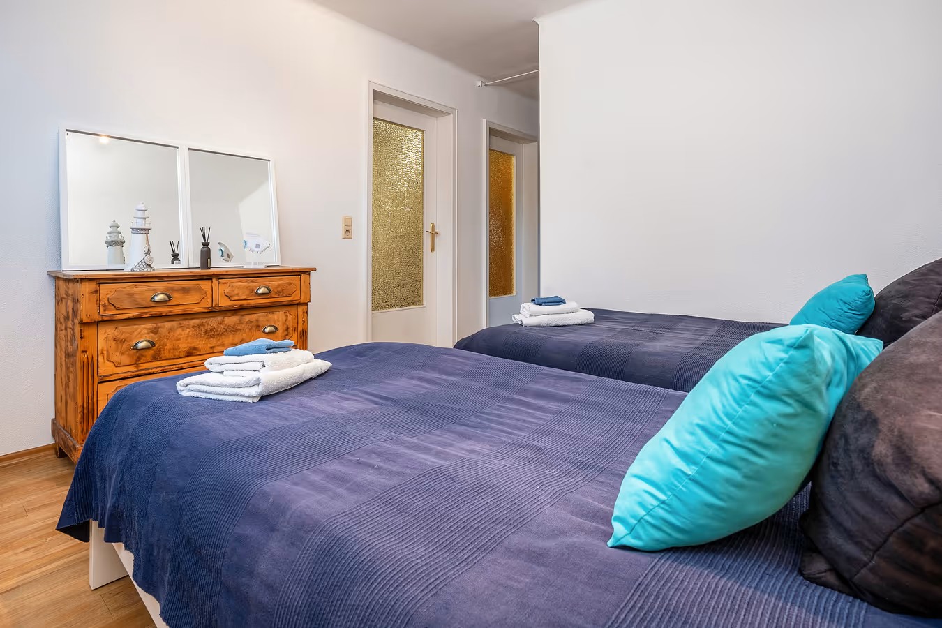 ferienwohnung bett im schlafzimmer mit türkisem kissen und blick auf kommode