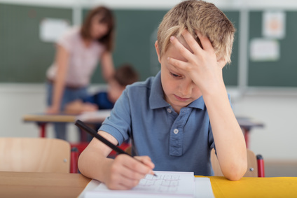 Junge, Bub in der Schule, Bub schreibt, Bub überlegt, Konzentrieren