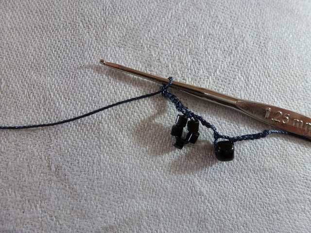 15. Nachdem das Perlengrüppchen eingehäkelt ist, bildet es ein kleines Blümchen. Zum Abschluß häkeln Sie noch einmal 1cm Luftmaschen.