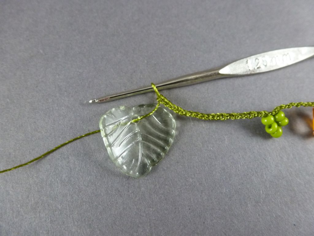 17. Nach der letzten grünen Perlengruppe häkeln Sie 20 LM. Holen Sie das erste Blatt bis an die Nadel.