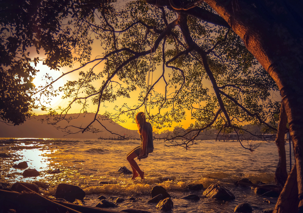 Silhouette einer Frau auf einer Strandschaukel bei Sonnenuntergang in Chumphon