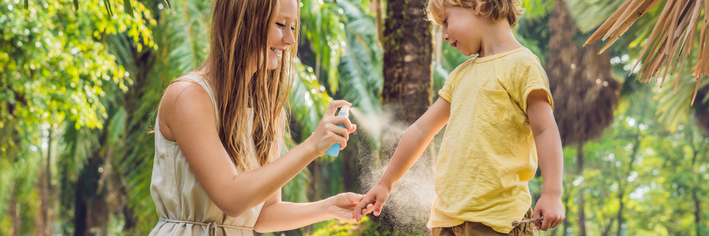Mutter sprüht ihren Sohn mit Moskitospray ein