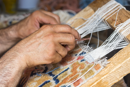 Defekte Ränder eines Teppiches werden bie der Teppichreparatur in Handarbeit neu geknüpft.