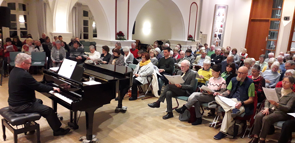 Begleitet von Thomas Sander am Klavier, singen die Gäste im vollen Saal der Musikschule Wetzlar Weihnachtslieder in mehreren Sprachen.