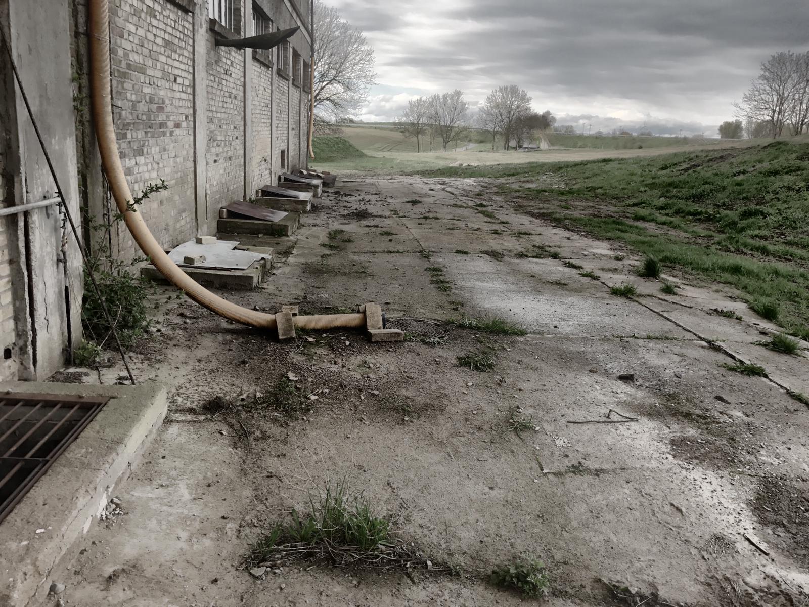 Originalzustand der östlichen Gebäudeseite vor dem Beginn der Freilegung der Kellerfenster und dem Rückbau der Betonumfahrung des Speichers. 