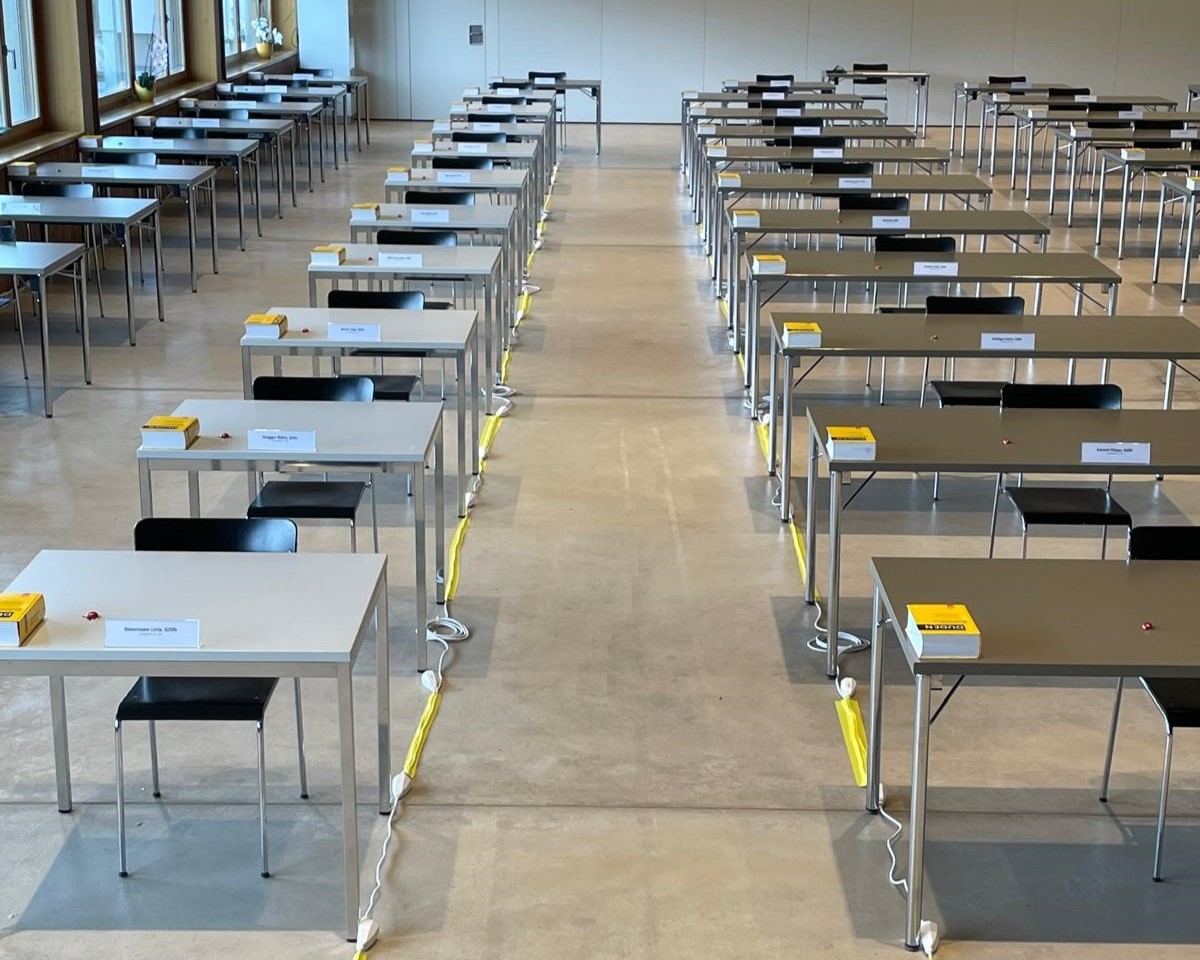 Für die Maturaprüfungen stehen die Tische mit Stromanschlüssen in der Aula der Kantonsschule Willisau in Reih und Gleid. (Bild: Kantonsschule Willisau)